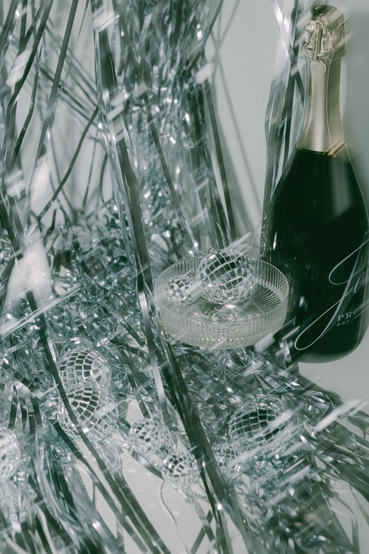 Crystal glassware and champagne bottle with silver holiday decorations.