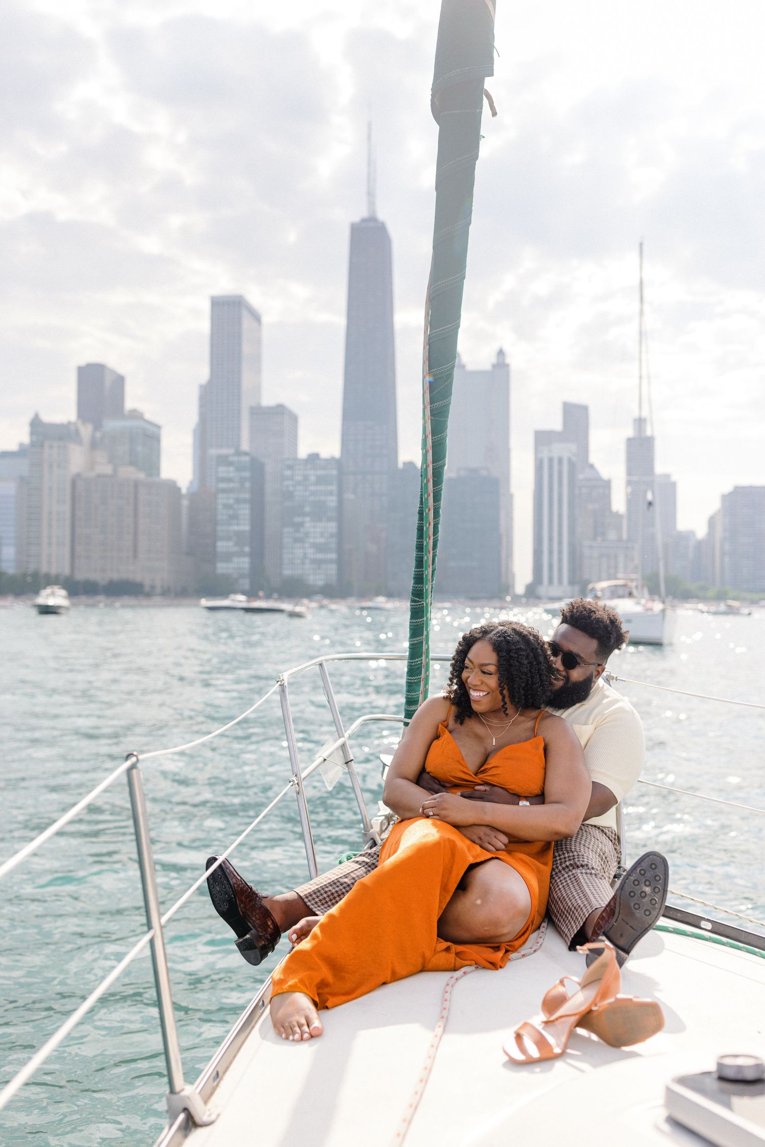 A couple relaxes on sailboat deck with Chicago skyline in background.