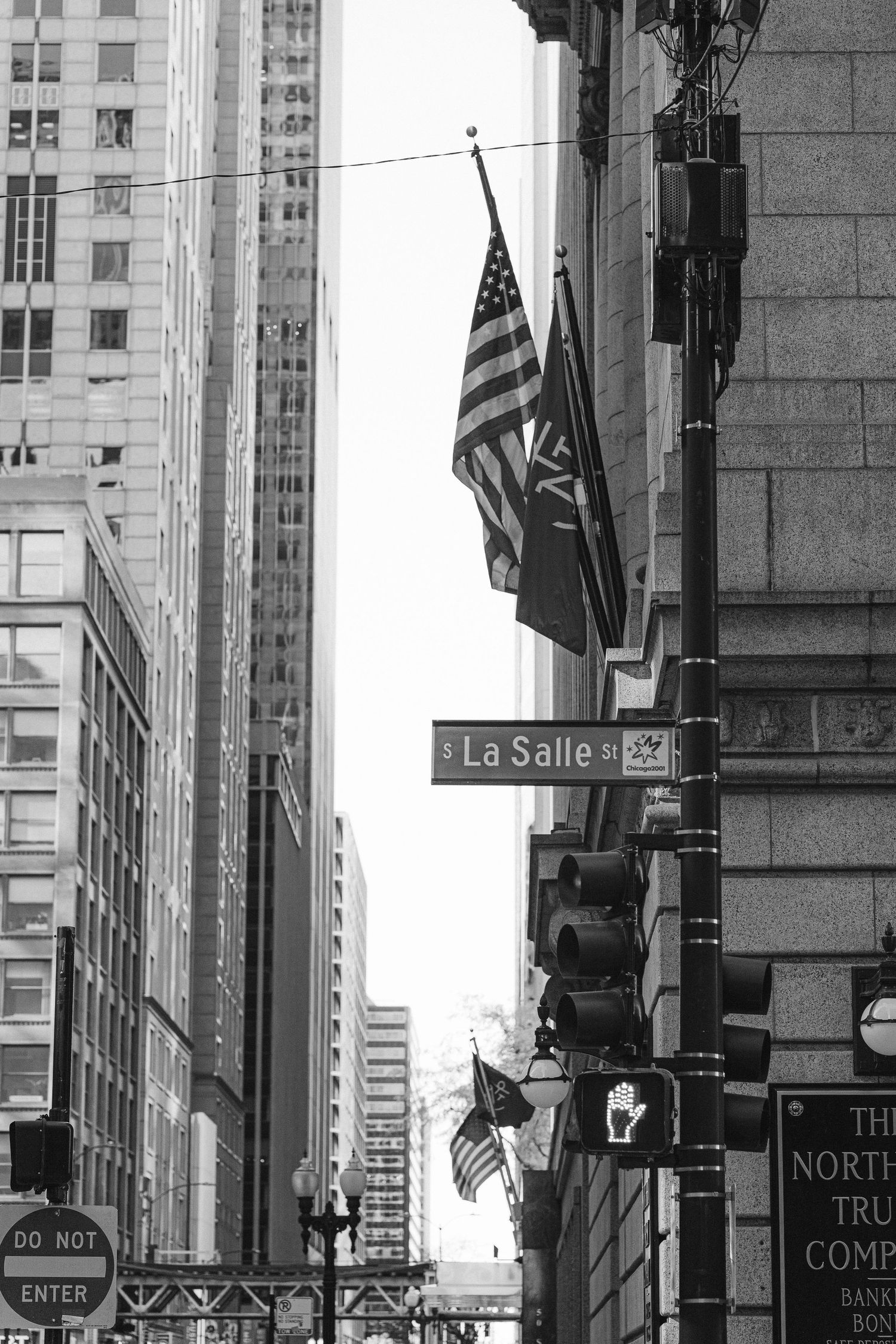 Black and white photo of La Salle street sign and American flags on a downtown Chicago building.