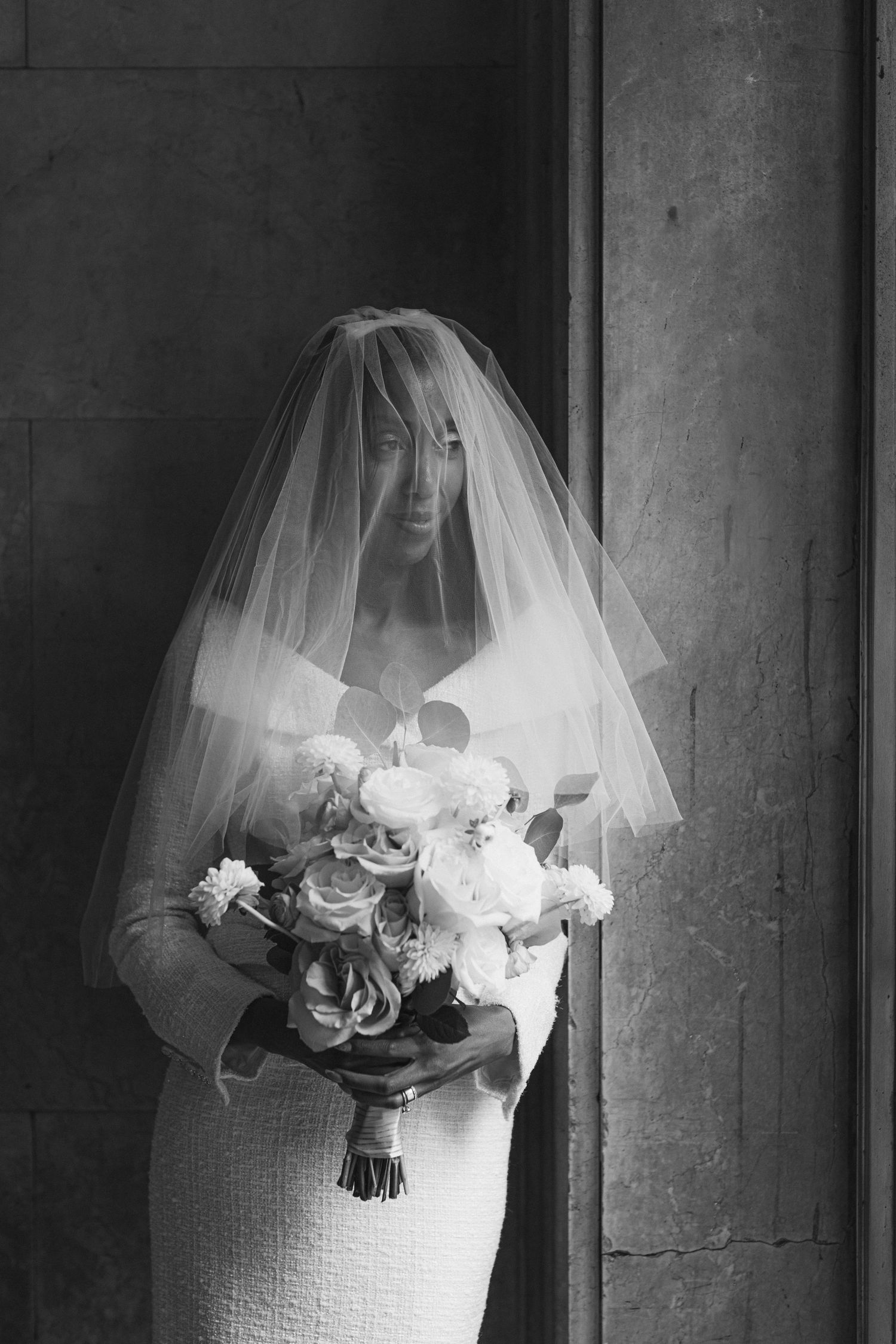 Artistic black and white bridal portrait showing a veil and white floral bouquet.