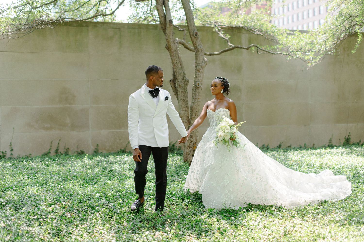 A couple in wedding attire standing together in a garden setting.