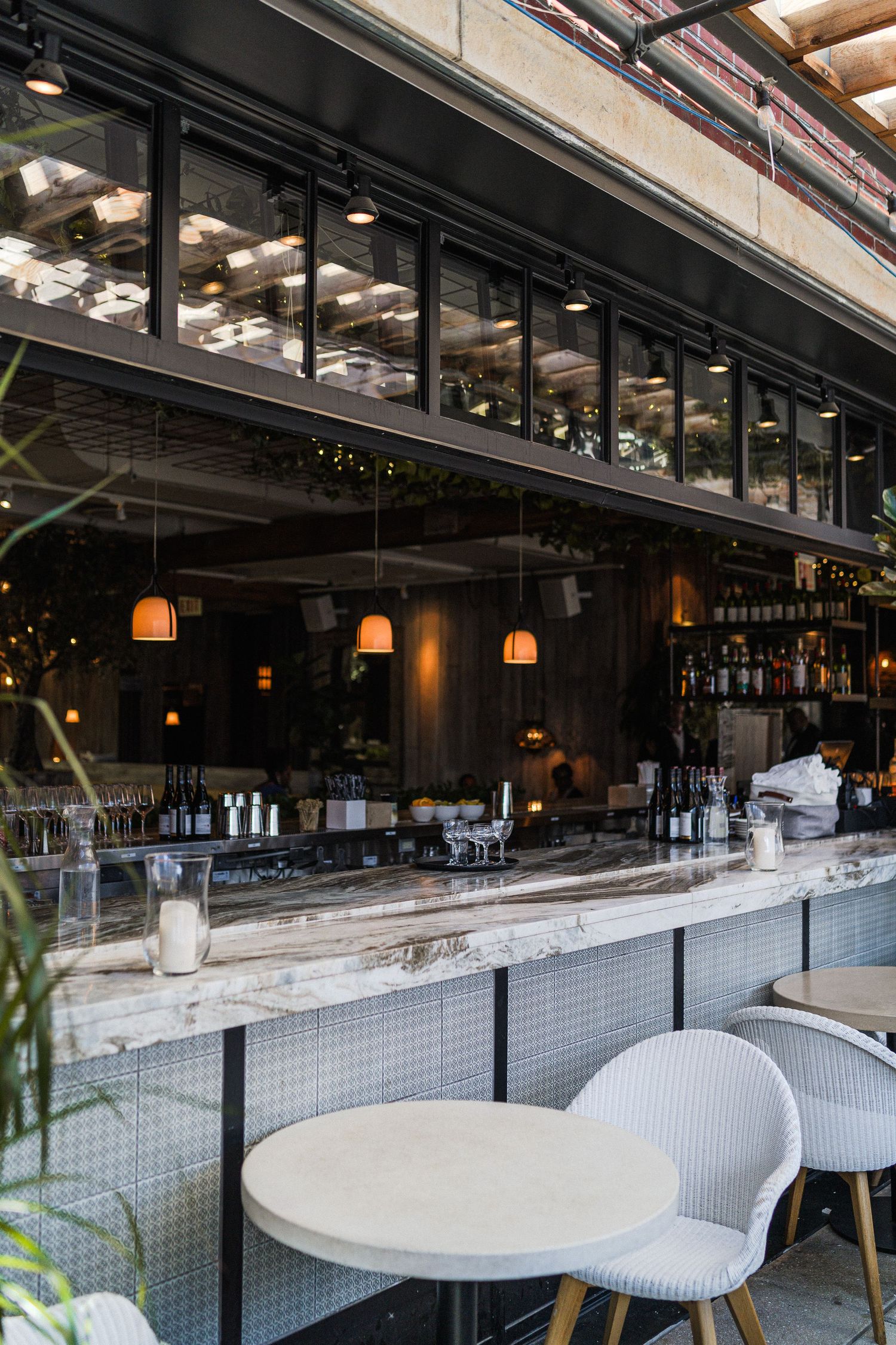 Modern restaurant bar with marble countertop, pendant lighting, and sleek industrial design.
