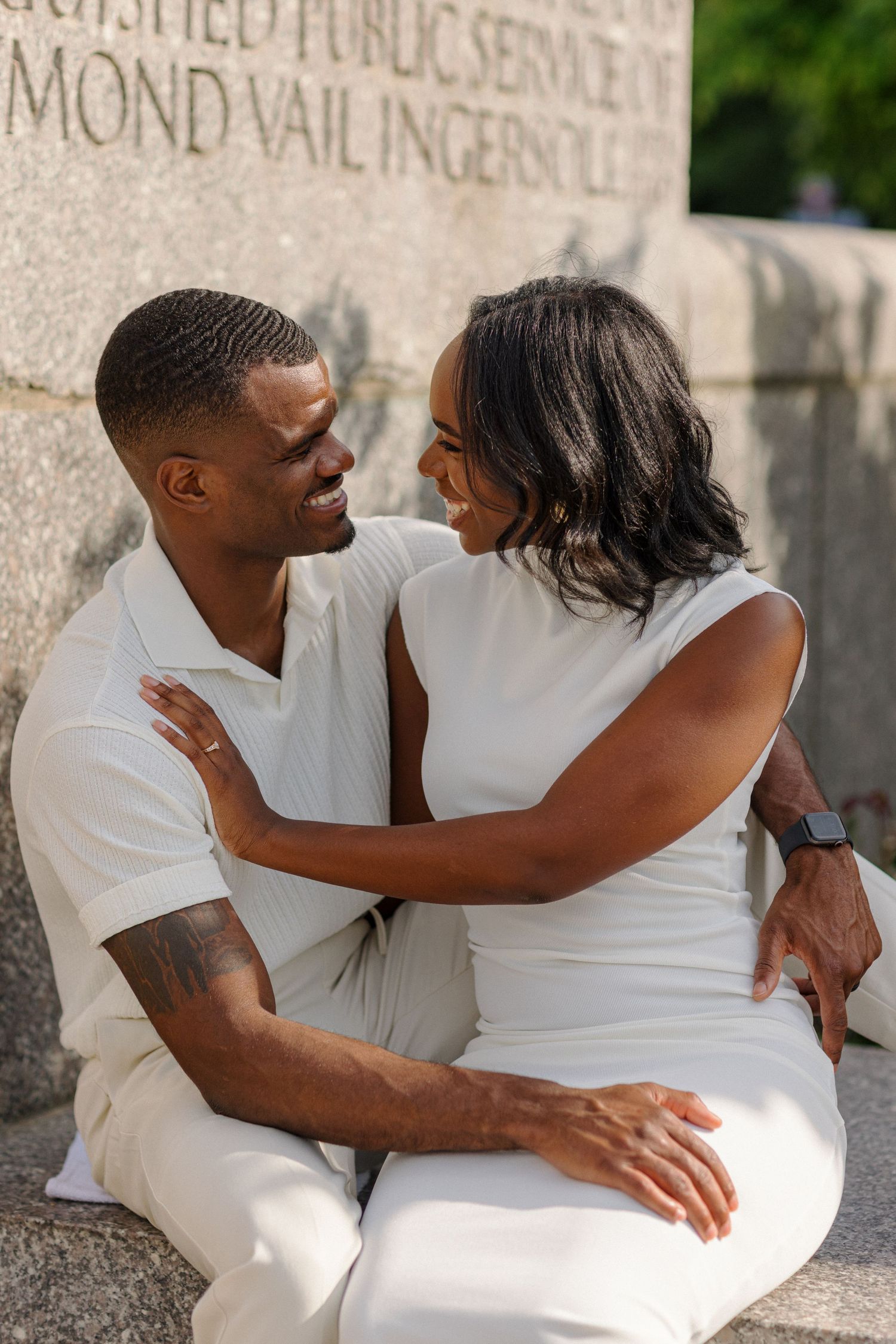A candid moment of a couple in white outfits sharing a warm embrace.