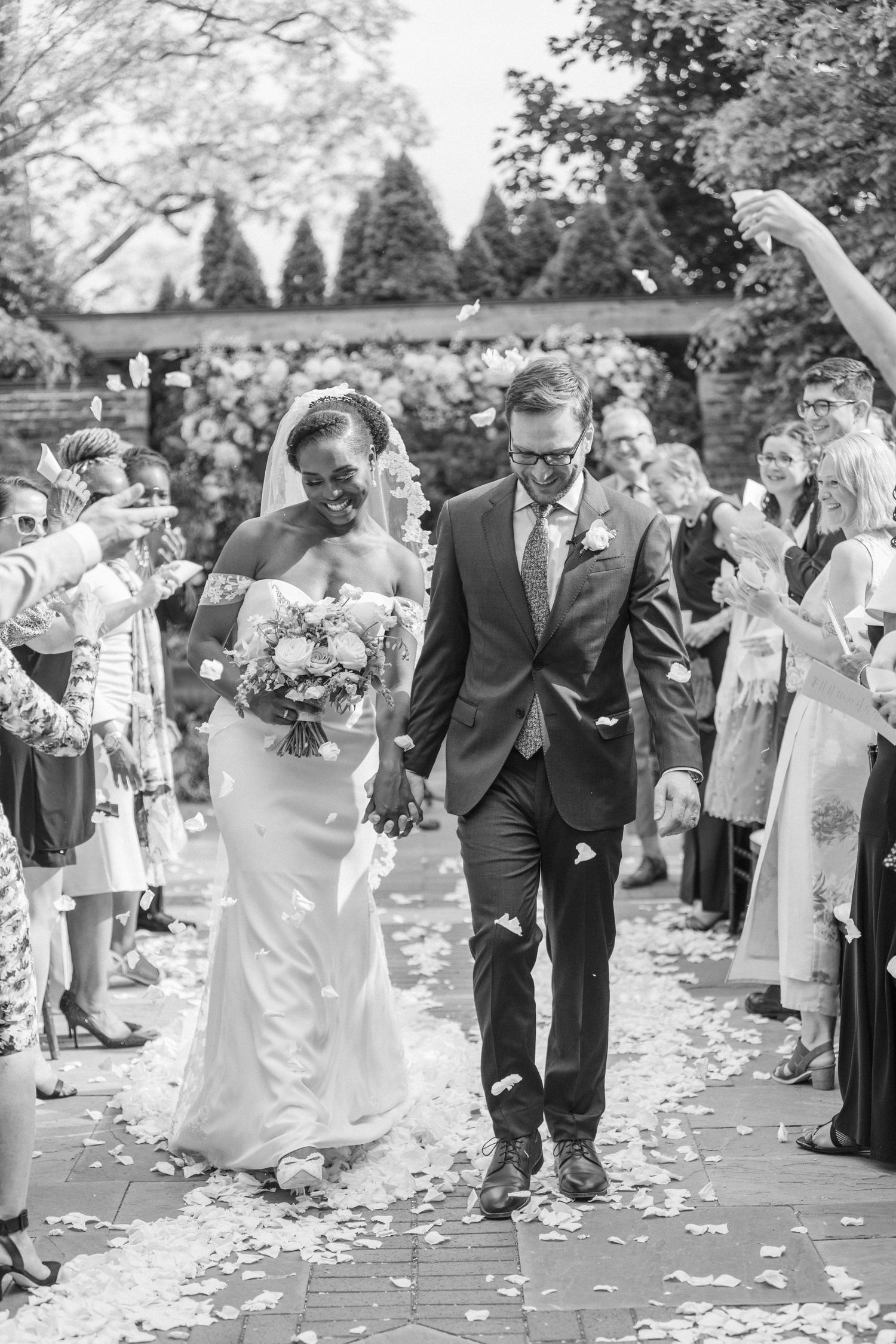 A joyful wedding recessional with guests throwing flower petals at the newlyweds.