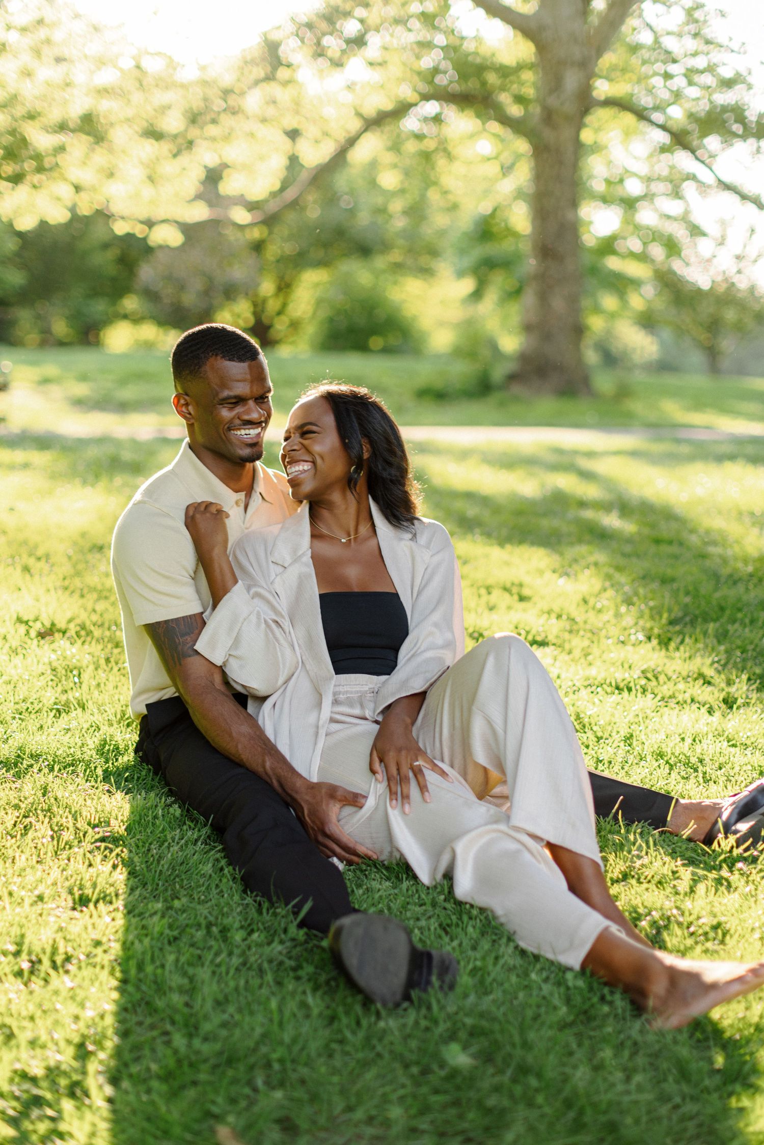 A couple relaxing together on grass during golden hour in a park.