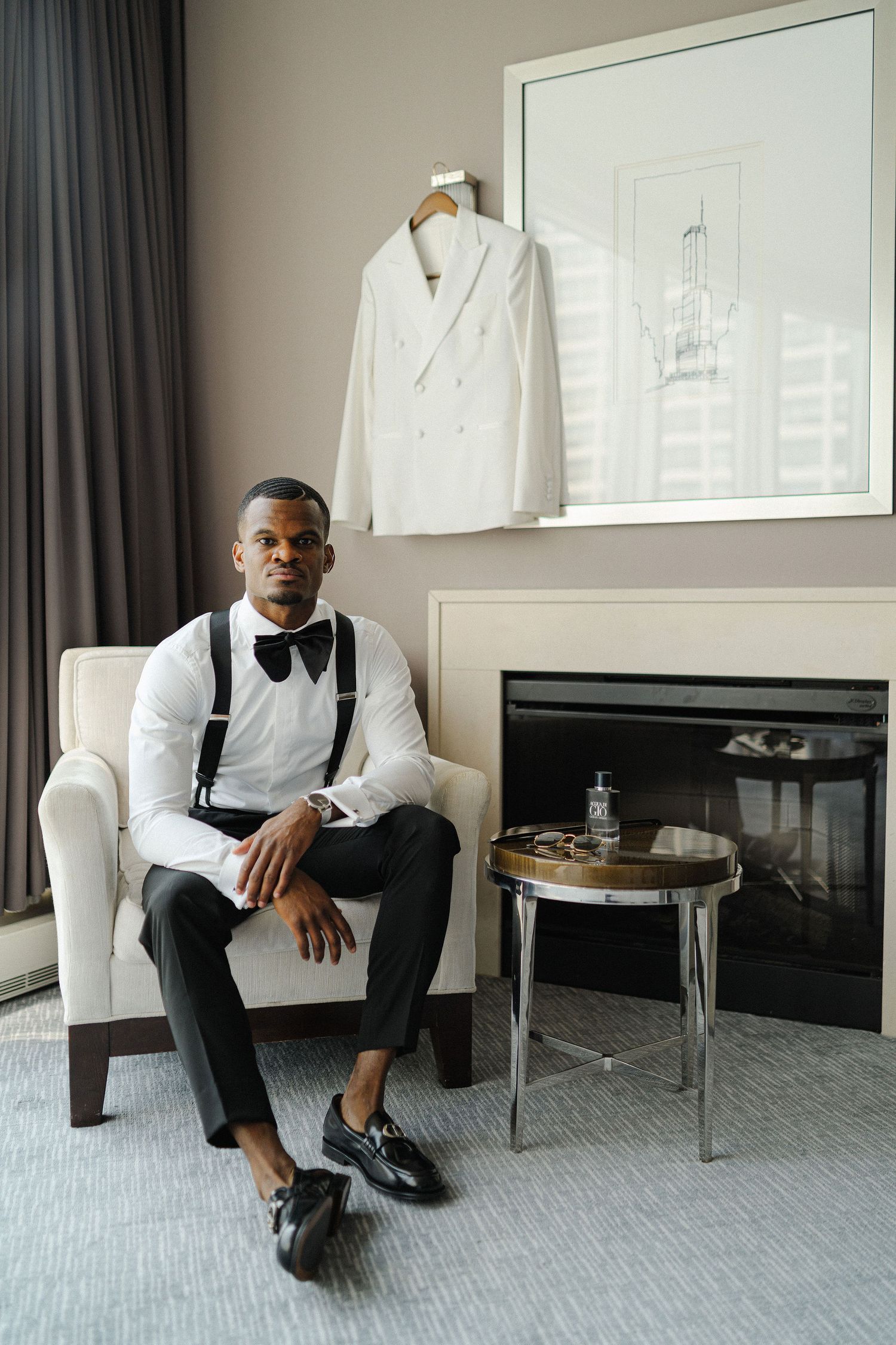 Formal attire with white tuxedo jacket displayed in modern room setting with fireplace.