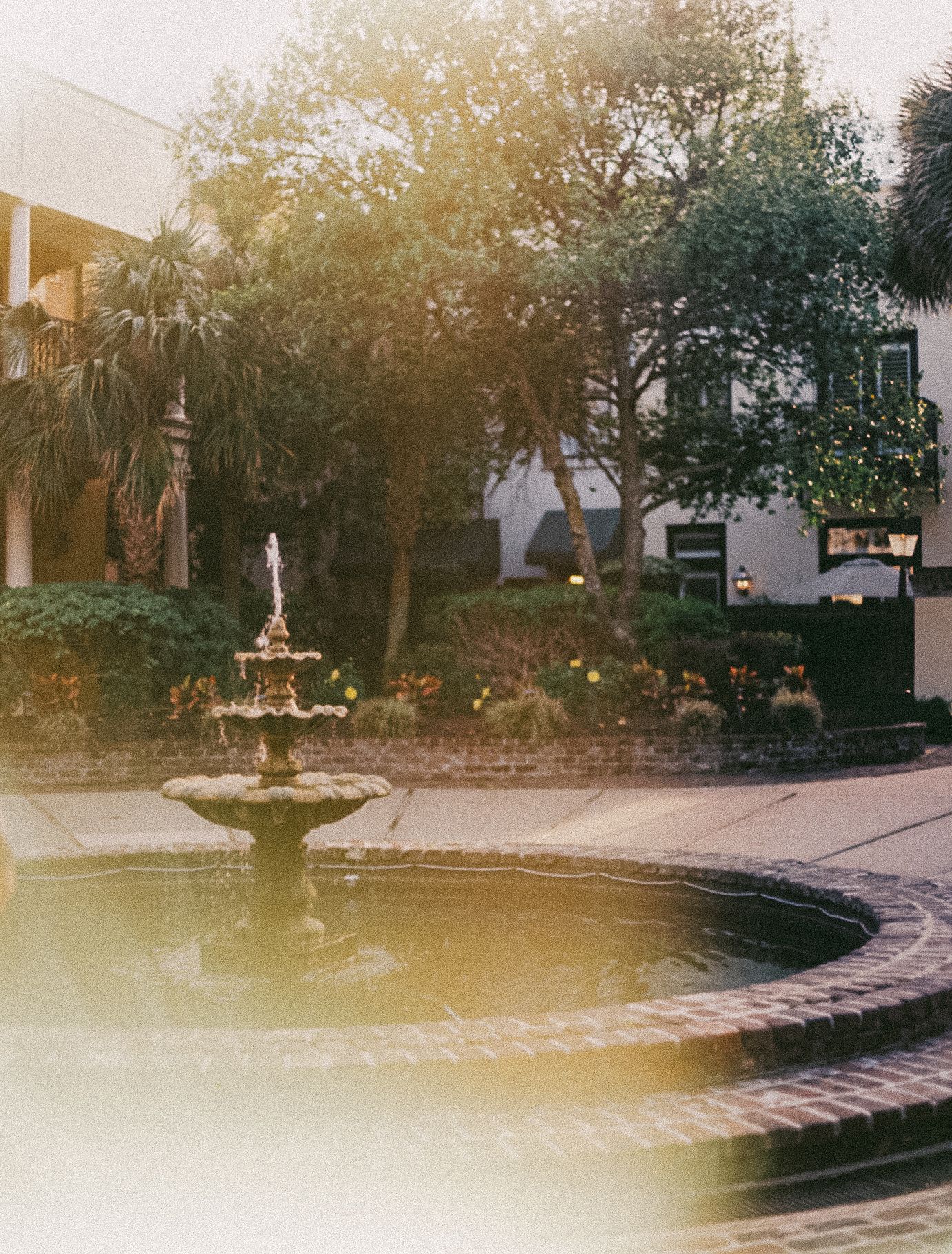 A serene fountain with water features sits in a tranquil garden courtyard during golden hour.
