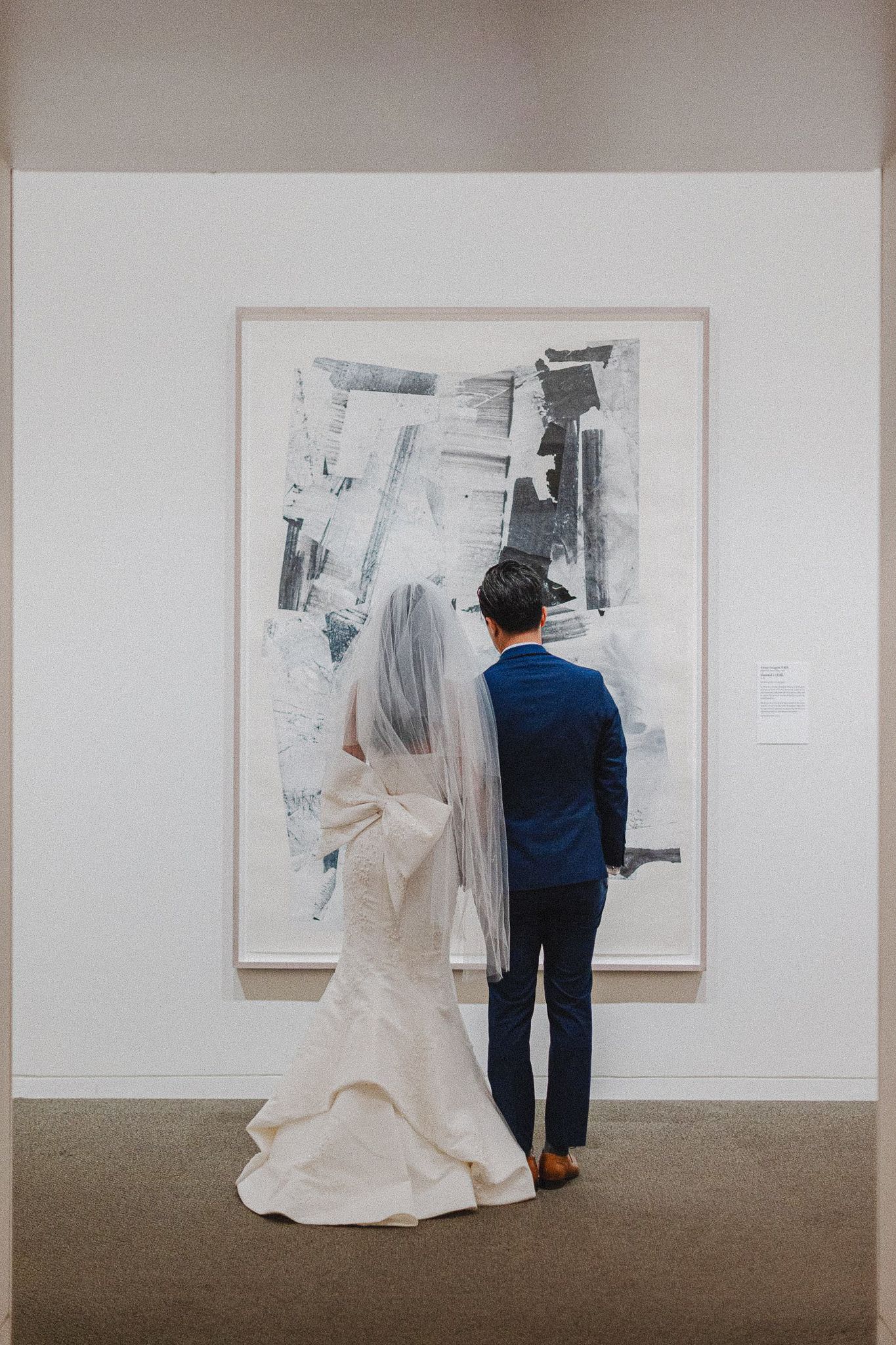 Newlyweds admiring modern black and white artwork in museum gallery.