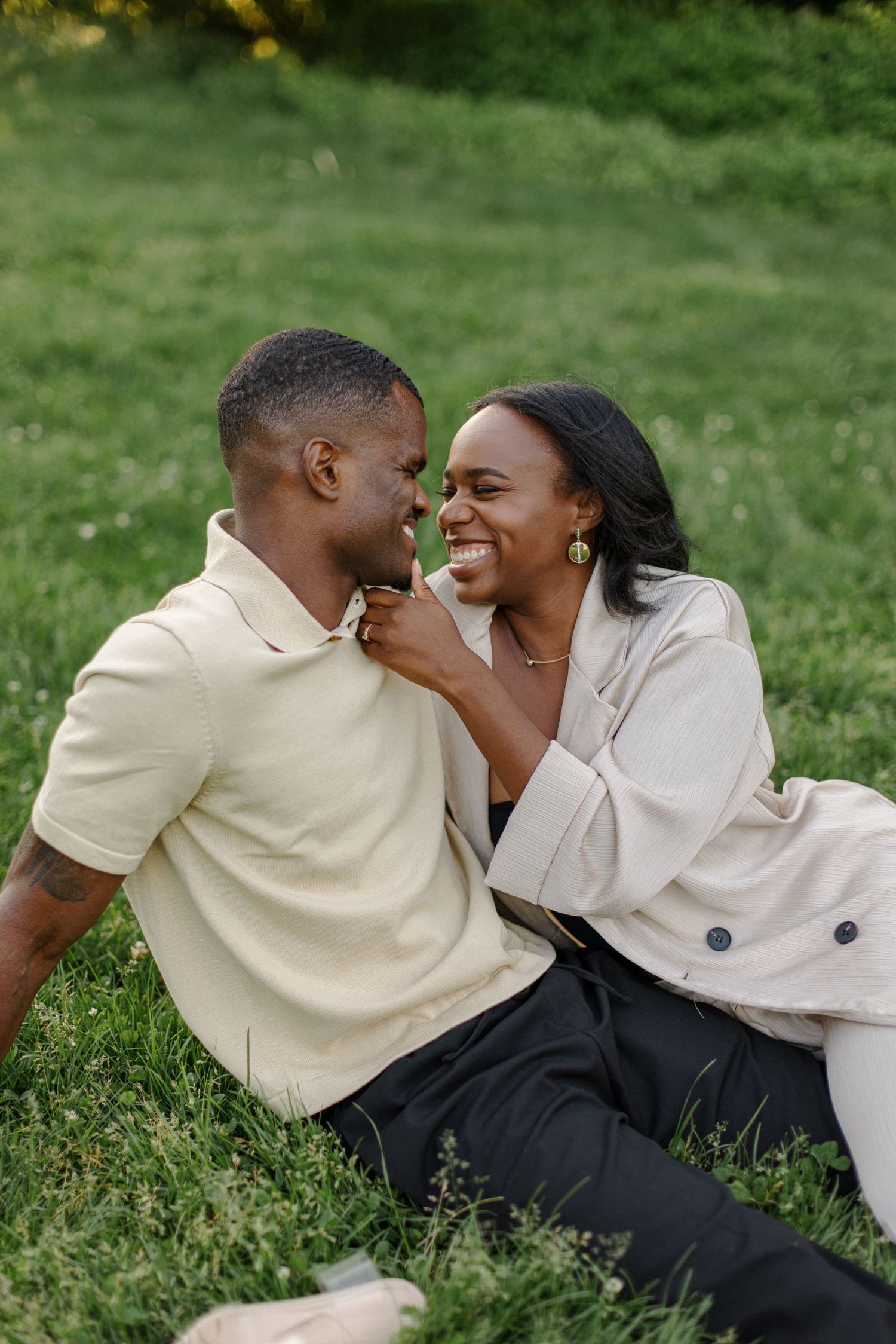 A couple sharing a tender moment while relaxing on grass in a park.