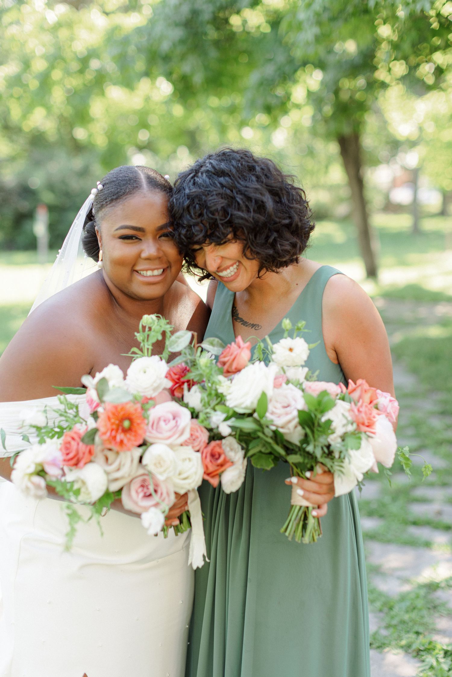 Wedding party members sharing a joyful moment with pink and coral floral bouquets.