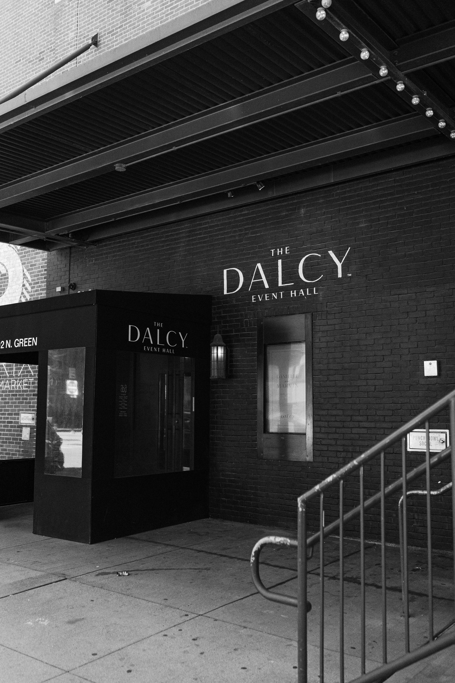 Black and white exterior shot of The Dalcy event space entrance with signage and metal railings.