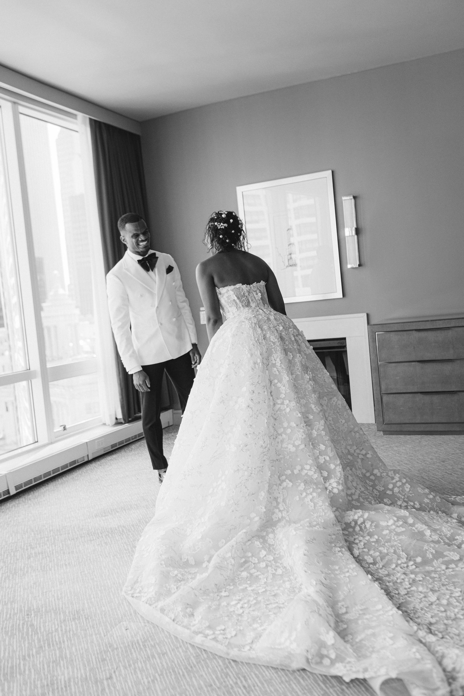 Elegant black and white wedding photo showing a flowing lace gown with long train.