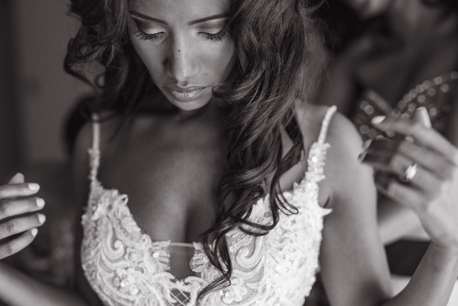 Moody black and white close-up of a bride in an elegant lace wedding gown.