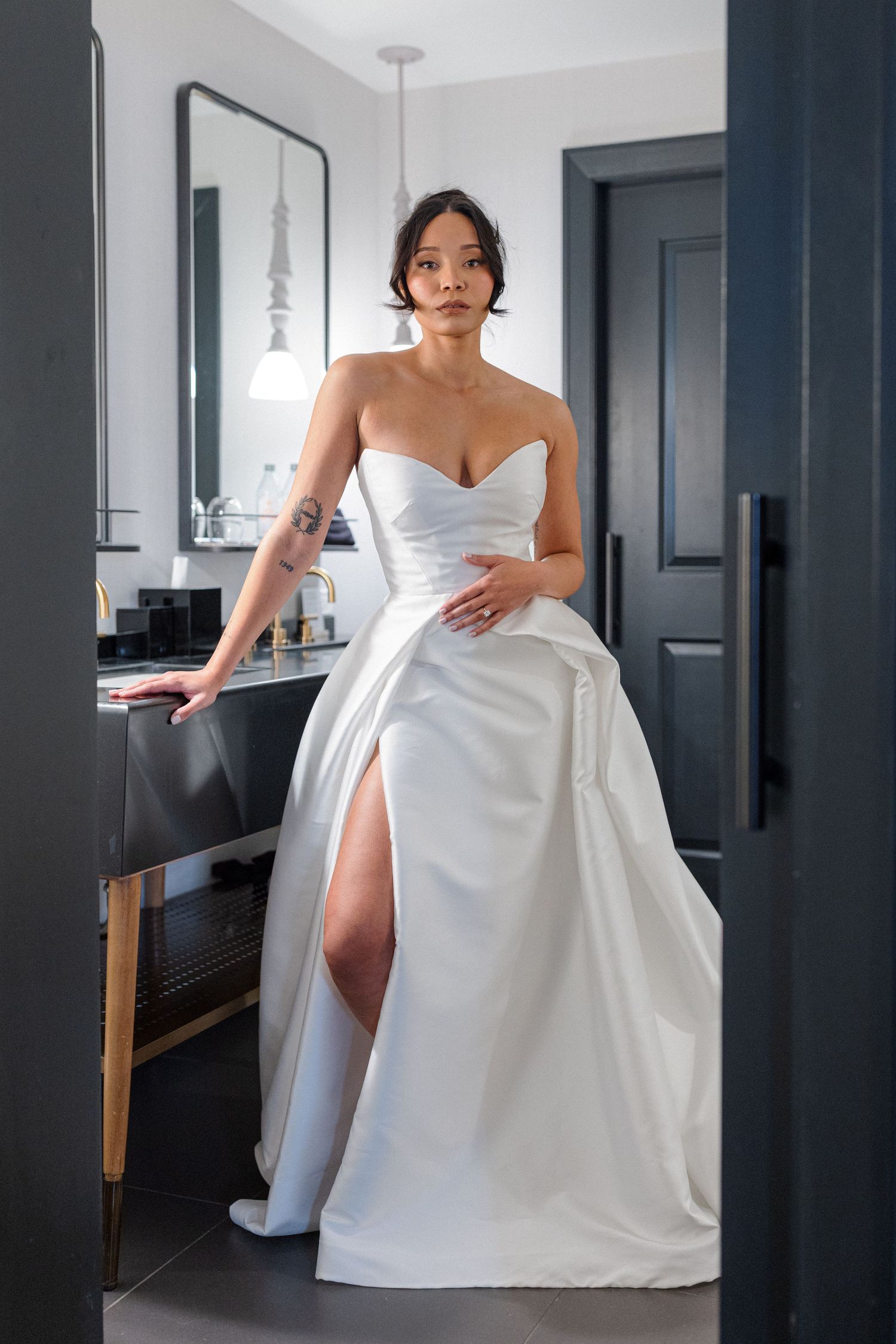 Modern white wedding dress with thigh-high slit and strapless design in contemporary setting.