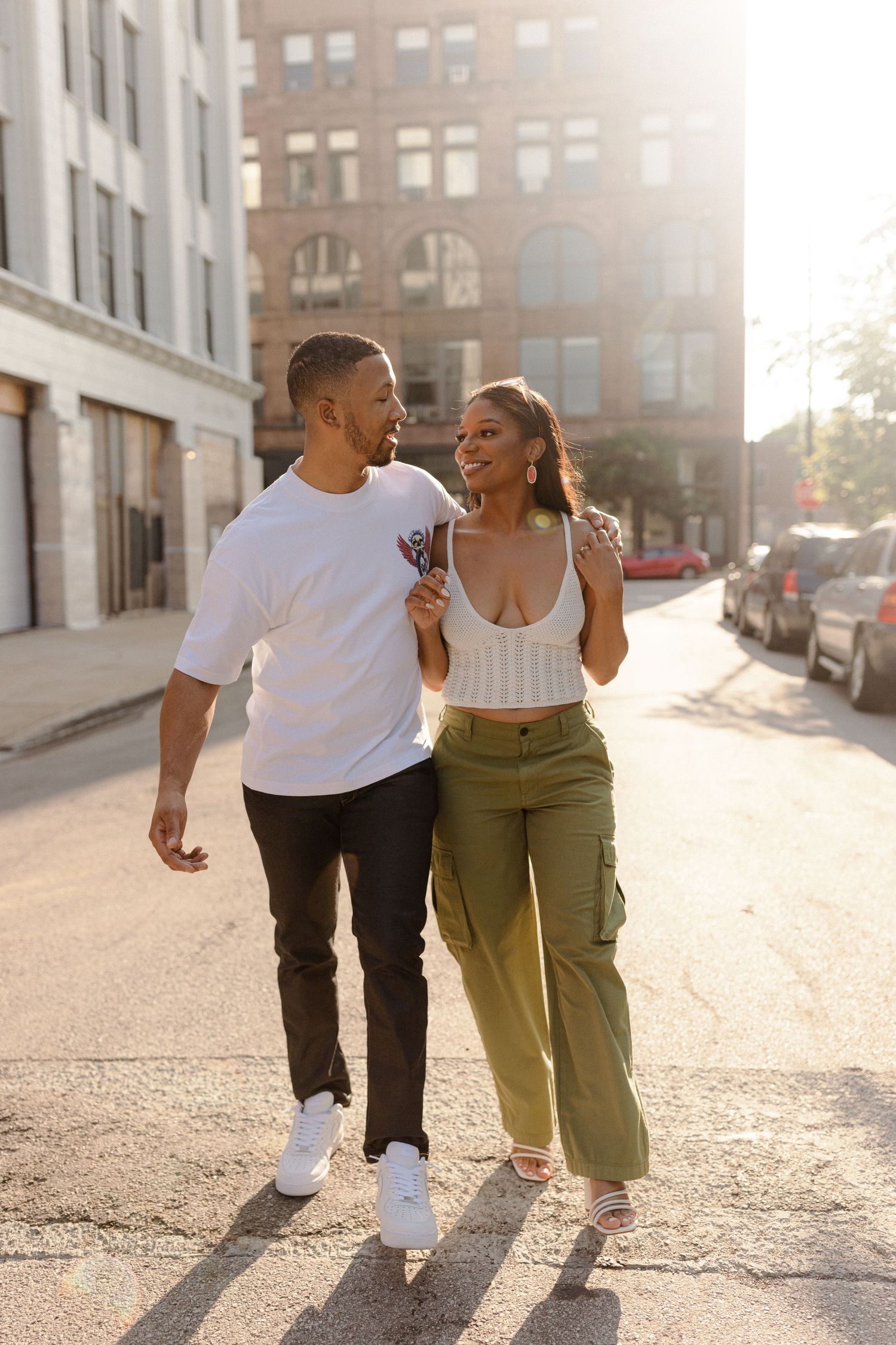 A couple walks together on a sunny urban street, laughing and embracing in a series of candid moments.