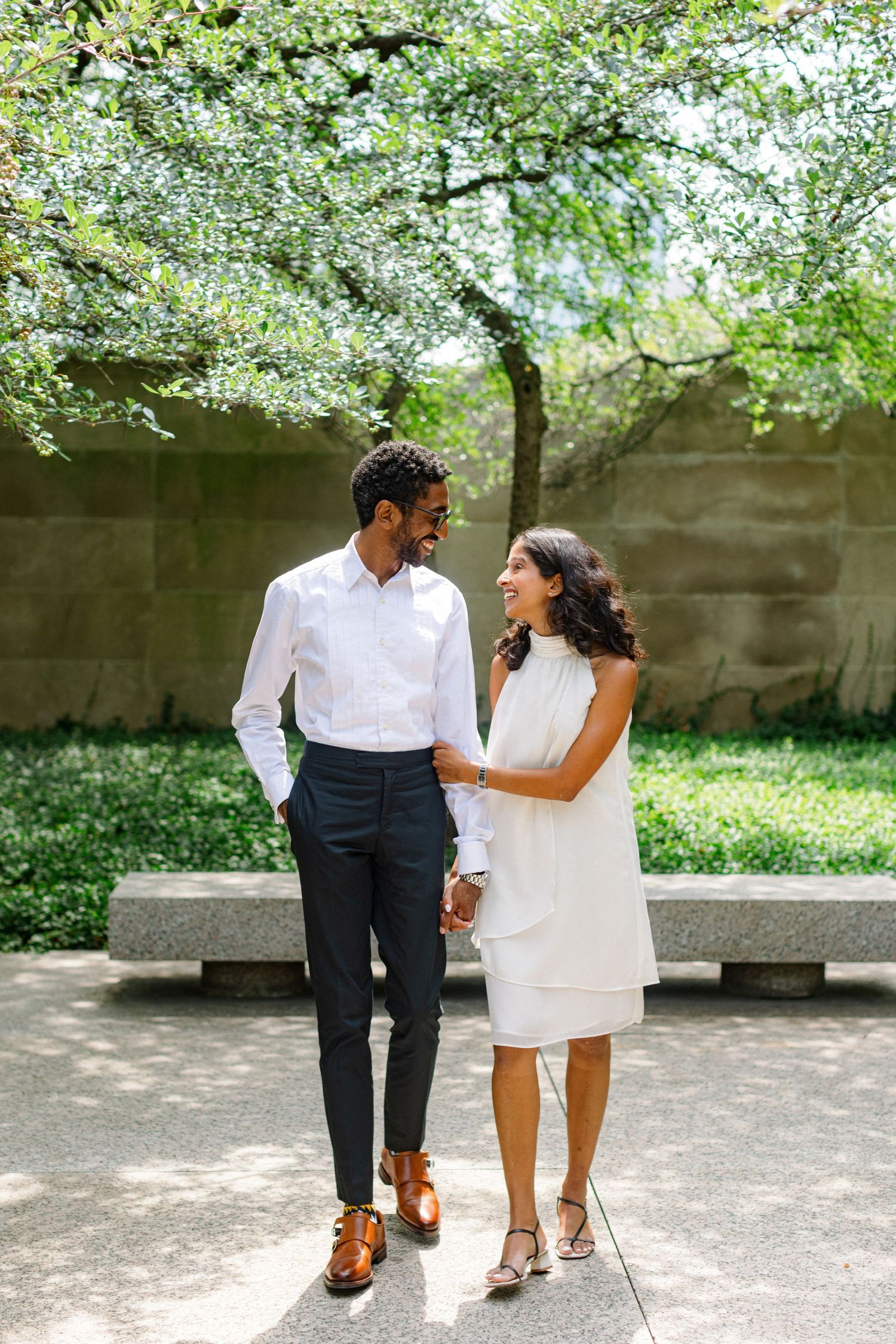 Stylish couple walking together in garden courtyard during spring photoshoot.
