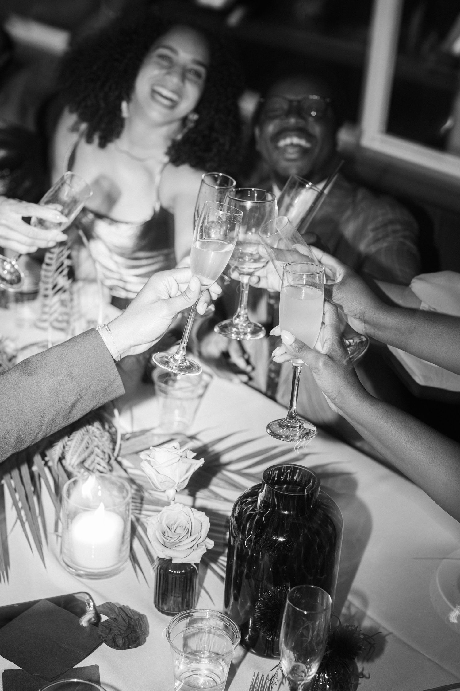 Wedding guests raising glasses in a celebratory toast at reception dinner.