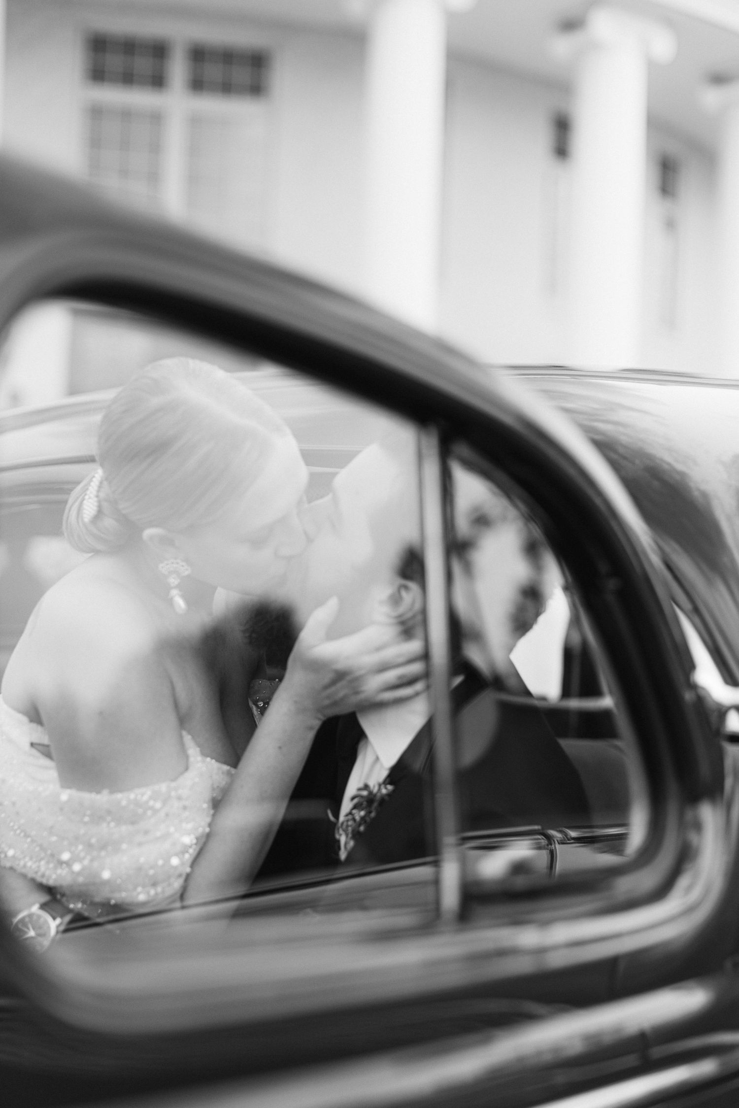 A romantic black and white moment captured through a vintage car window.