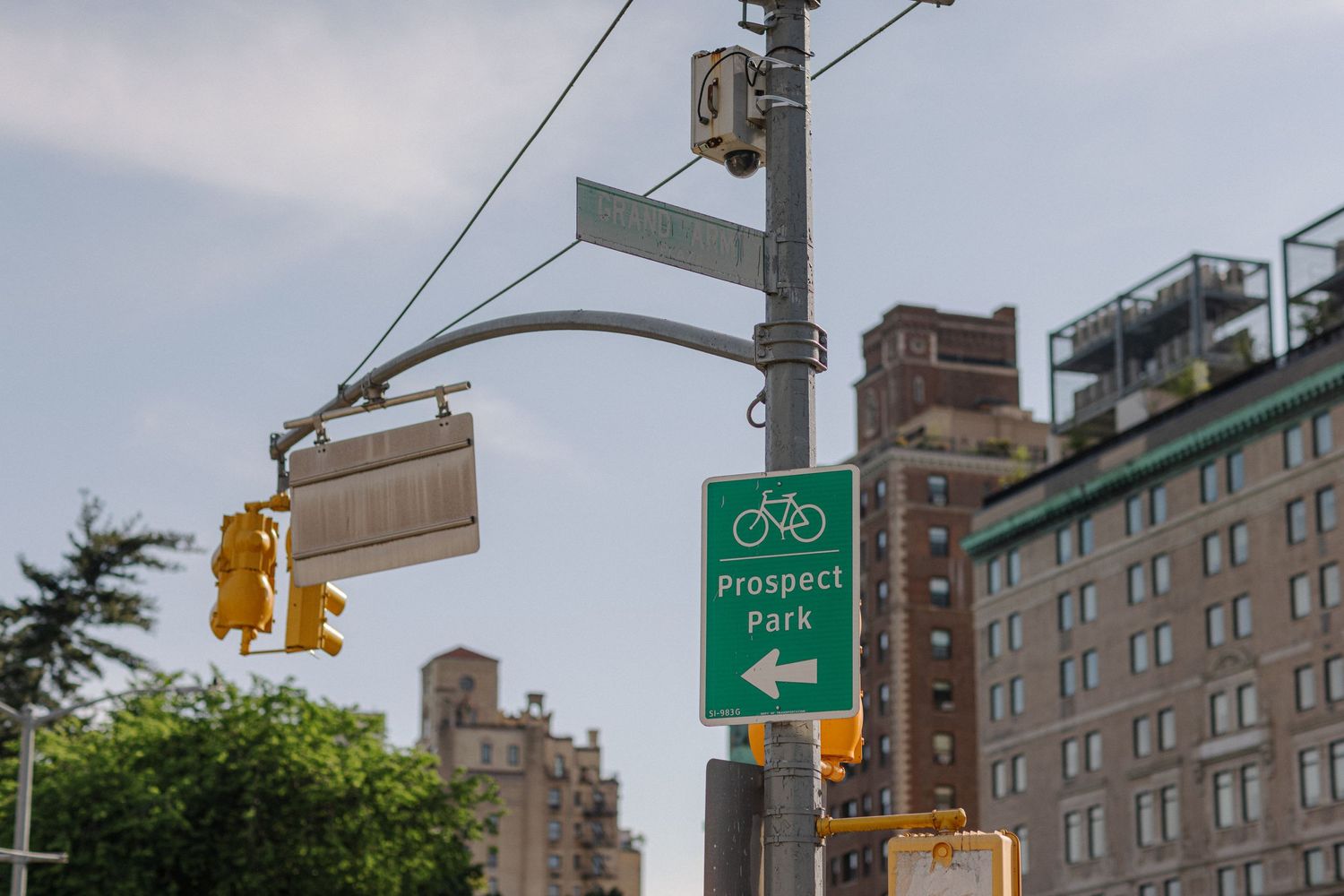 Urban street scene with traffic lights and bicycle route signs against city buildings.