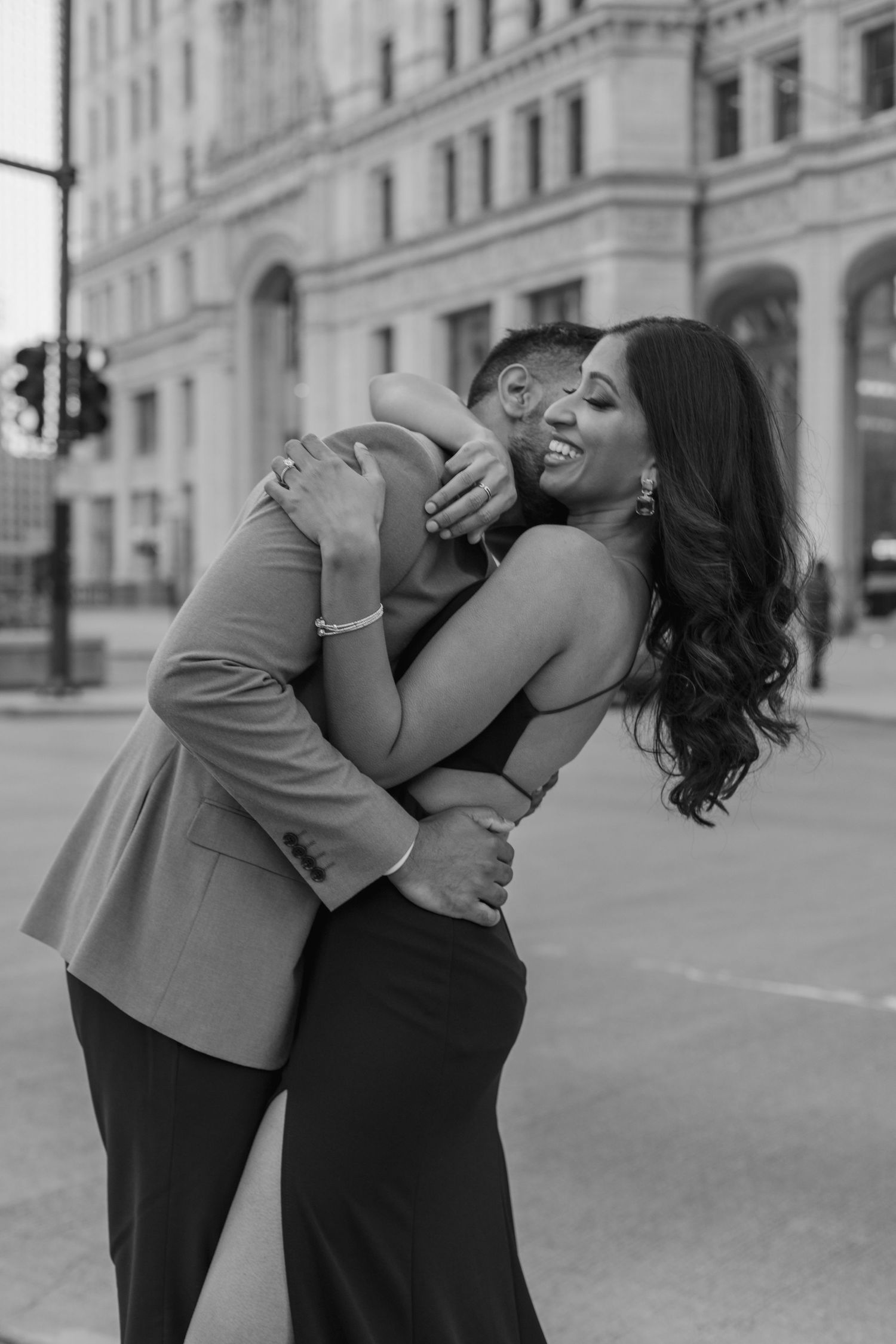 Couple sharing an intimate playful moment in formal attire on city street.