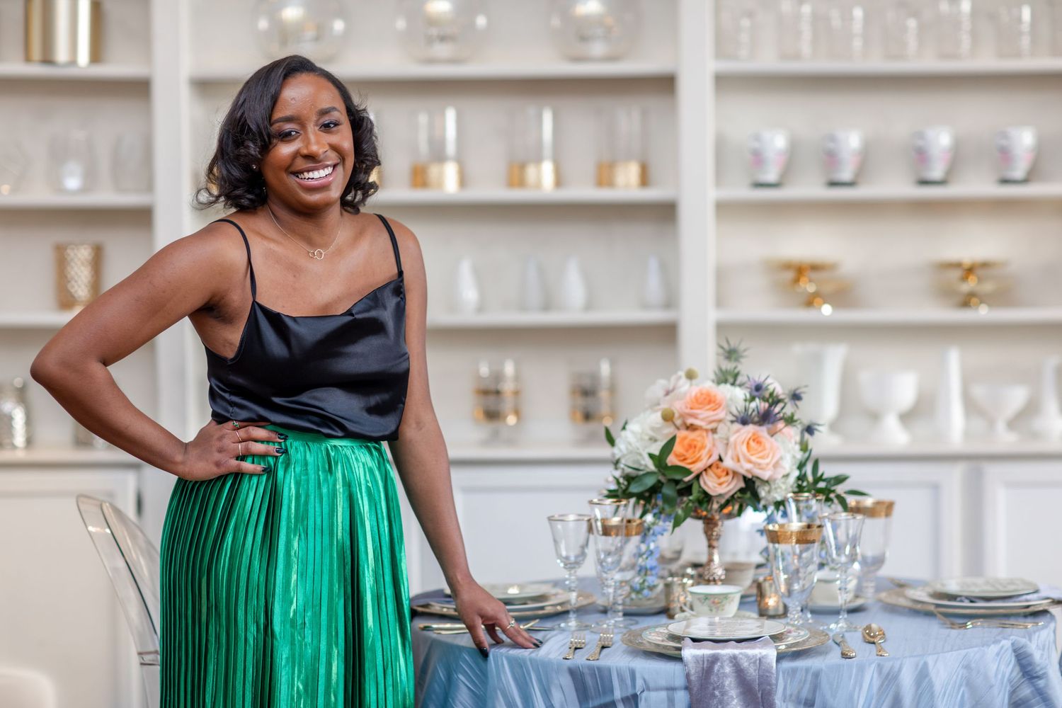 An elegant emerald green skirt and black top ensemble is pictured next to a beautifully decorated wedding reception table.