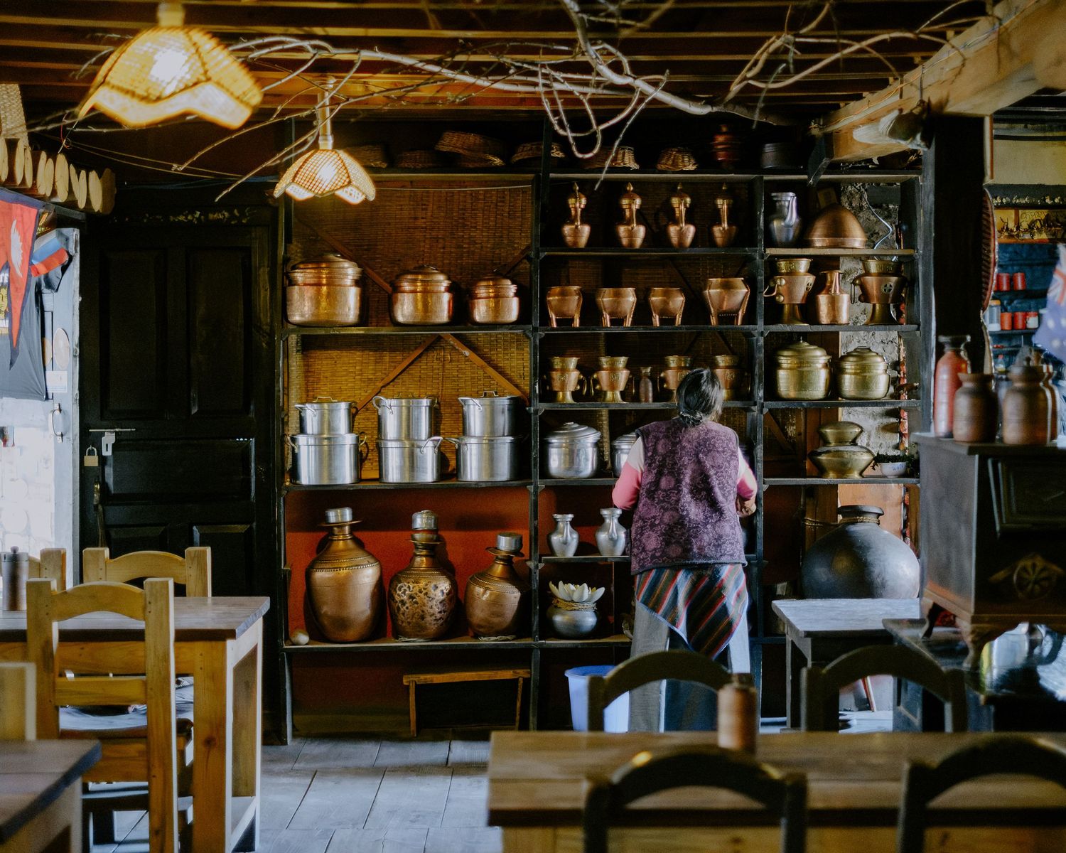 A dimly lit traditional Japanese shrine interior with wooden architecture and hanging lanterns creating an atmospheric ambiance.