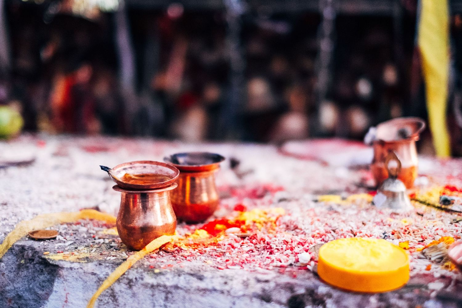 Copper vessels and religious offerings arranged on a stone surface with colorful powder.