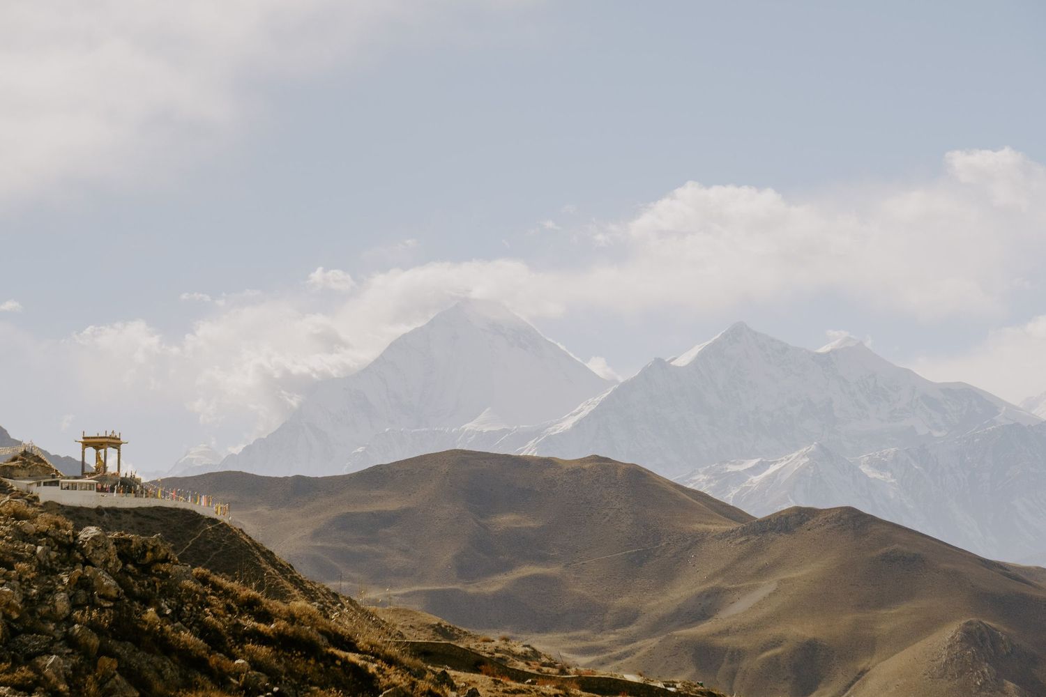Dramatic mountain range with snow-dusted peaks stretching across the horizon under a bright blue sky.