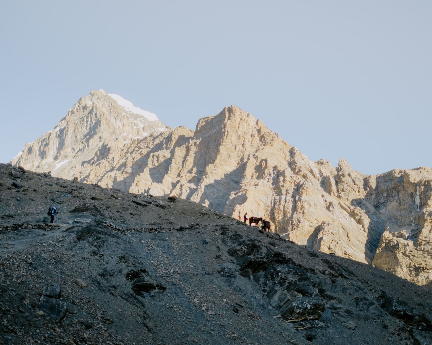Rugged mountain landscape with jagged peaks and rocky terrain under clear blue skies.