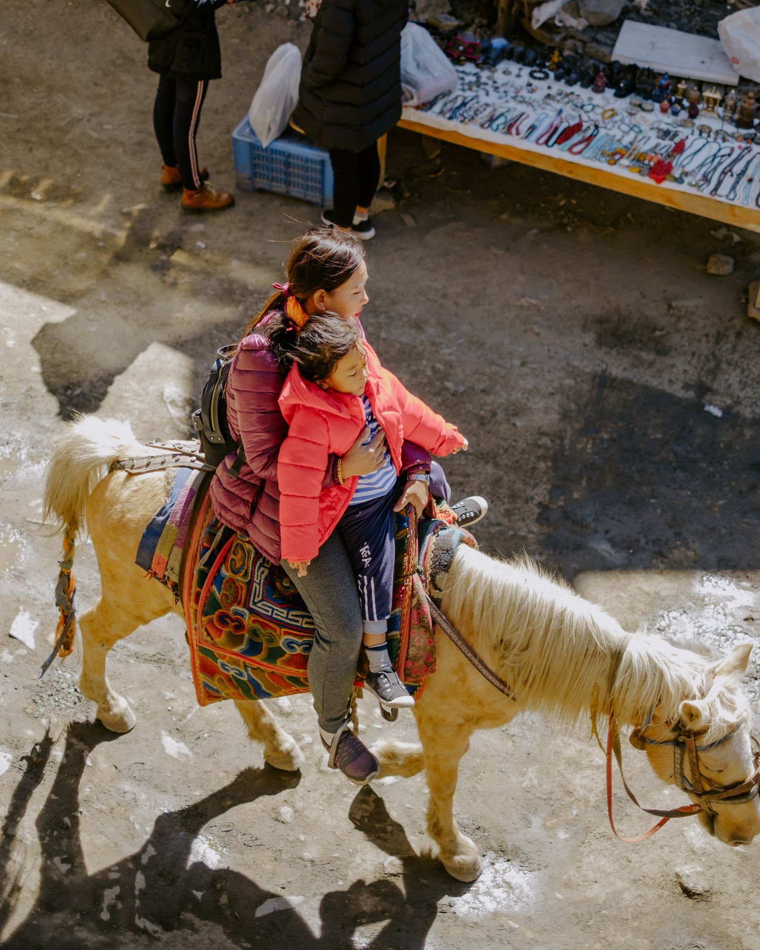 A sequence of images showing a child riding a pony at a carnival or fair while wearing a coral-colored jacket.