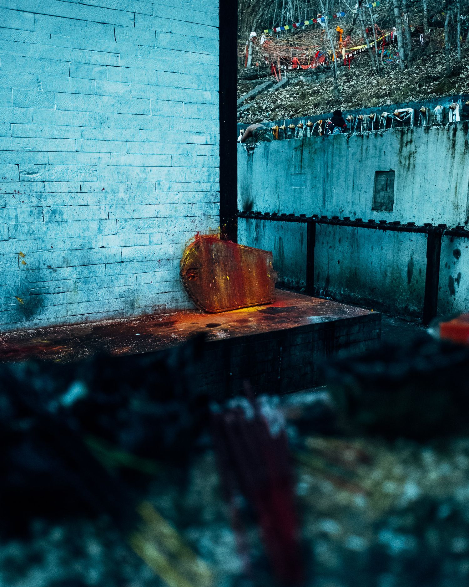 Moody blue-tinted interior with brick wall and wooden furniture in low light.