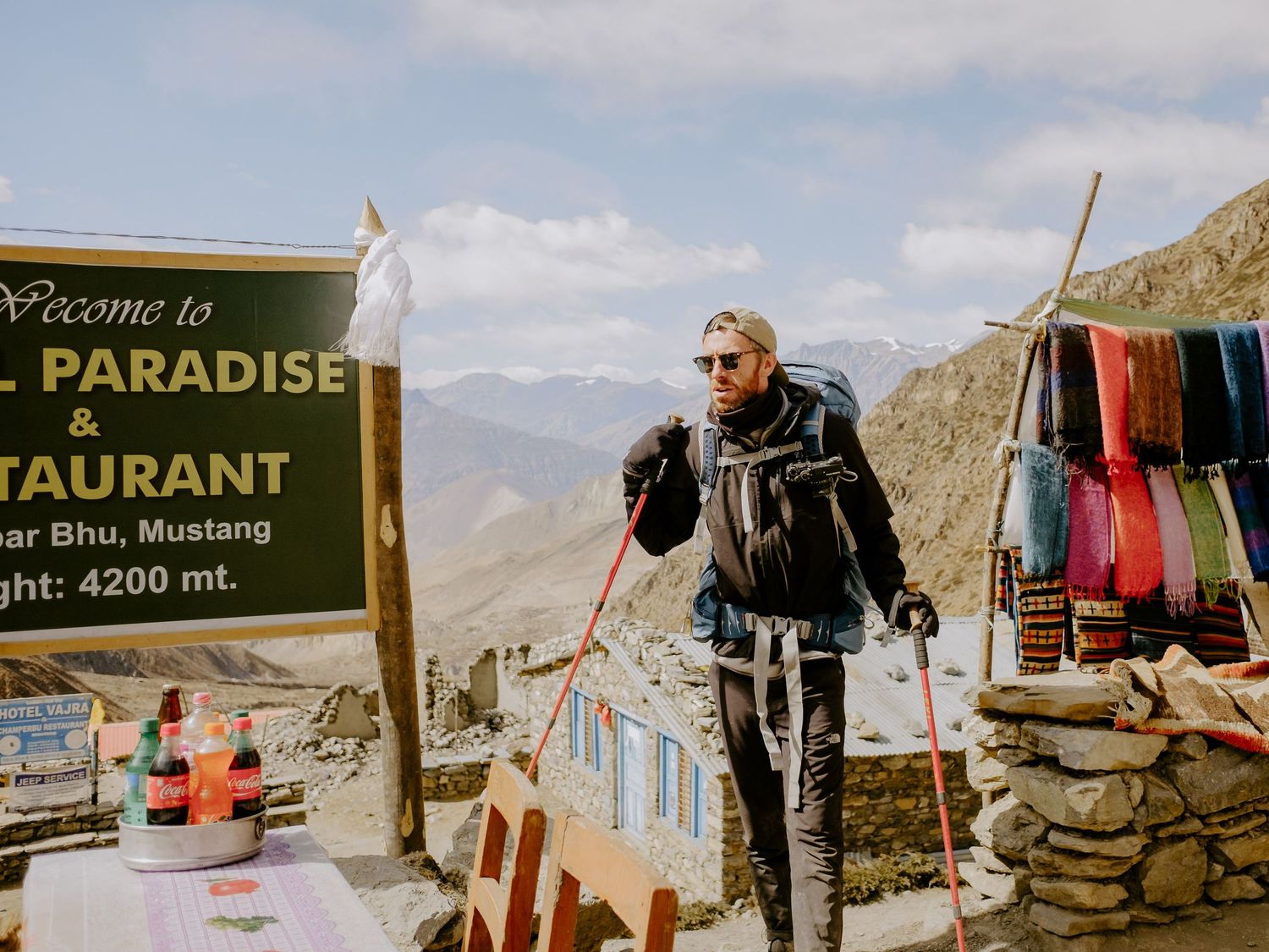 Mountain rest stop with colorful signs and vendor stalls along a remote hiking trail.