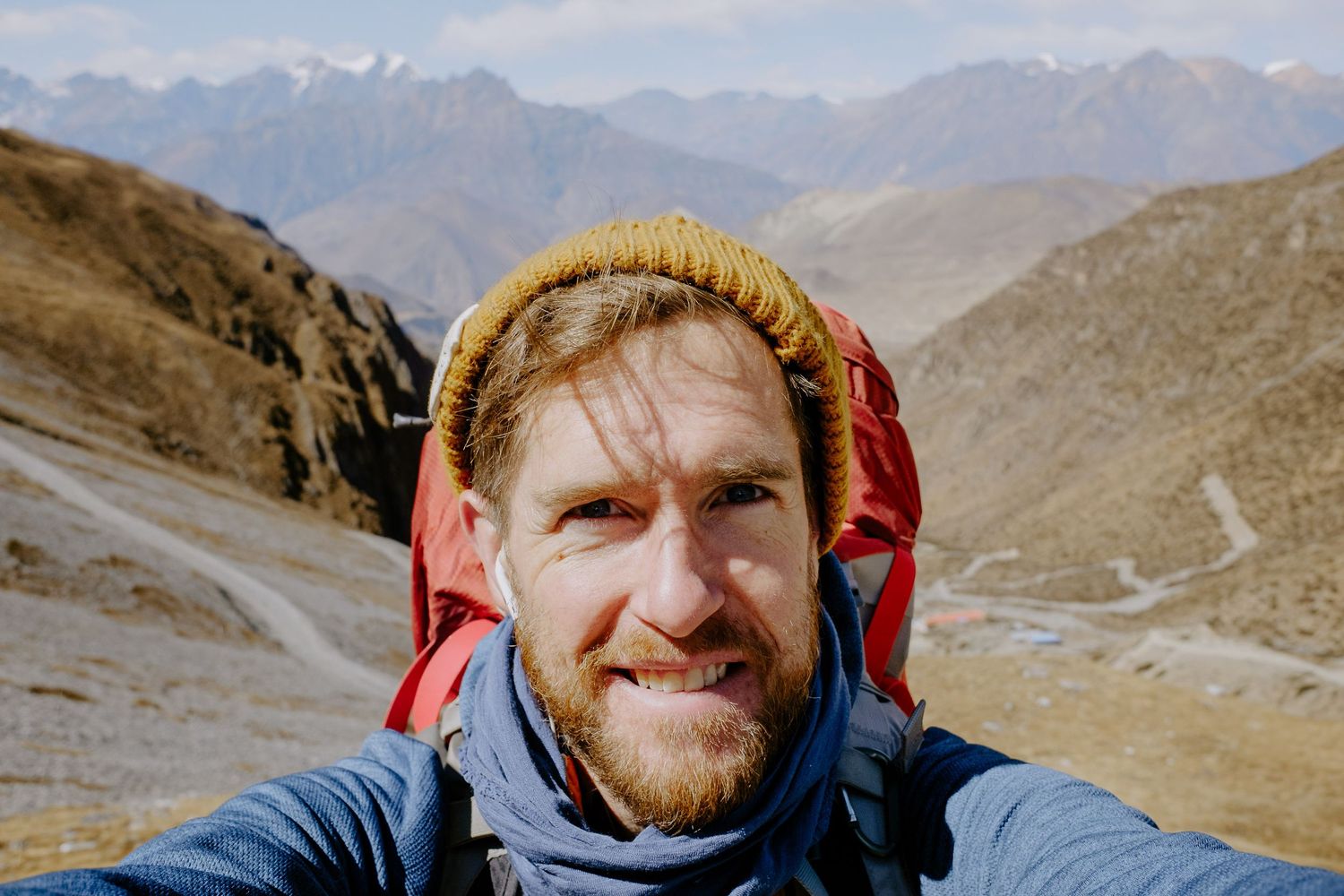 Adventurer wearing winter gear against backdrop of mountain peaks.