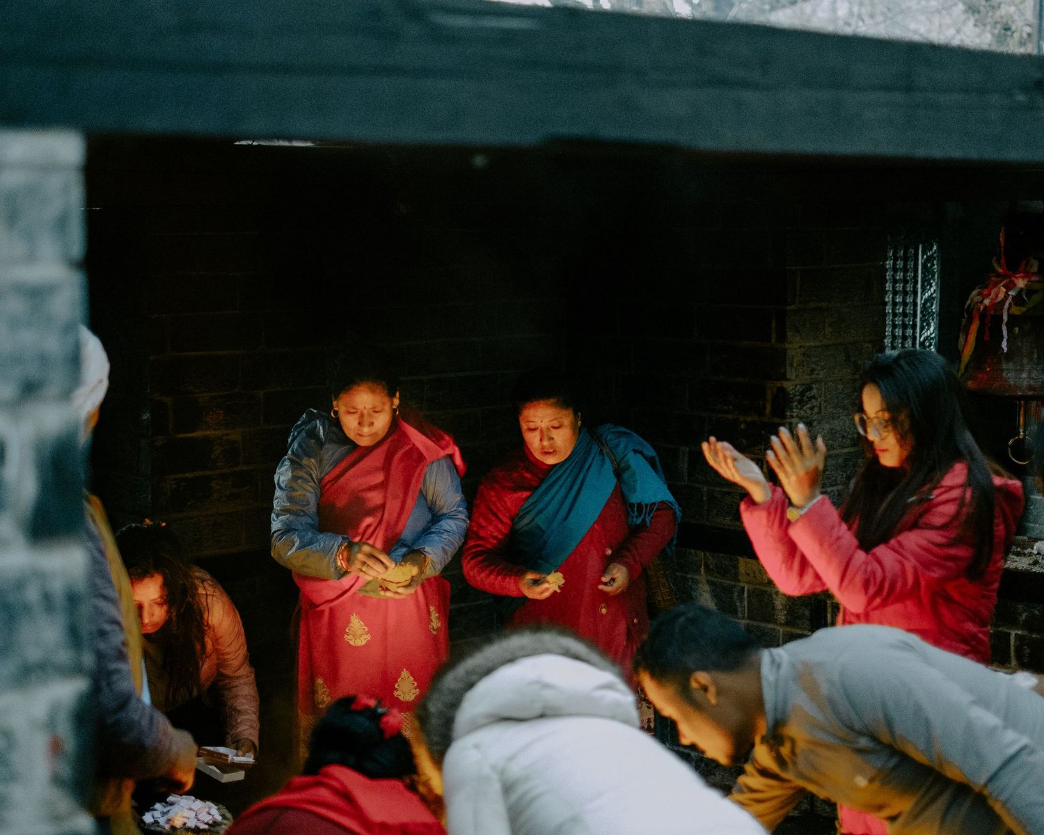 People gather in a dimly lit room wearing red and blue clothing.