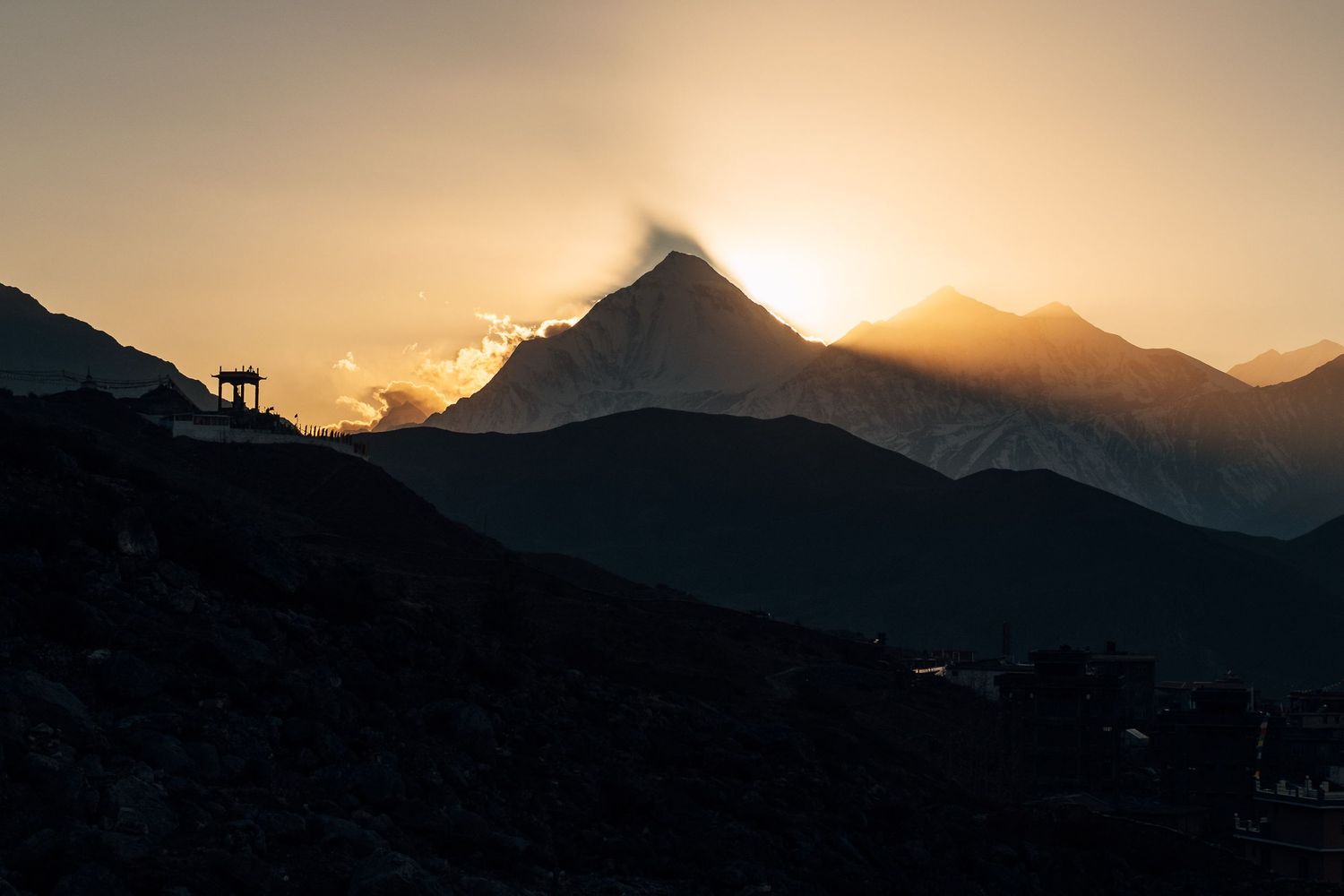 Mountain peaks silhouetted against a golden sunset sky create a dramatic panoramic landscape view.