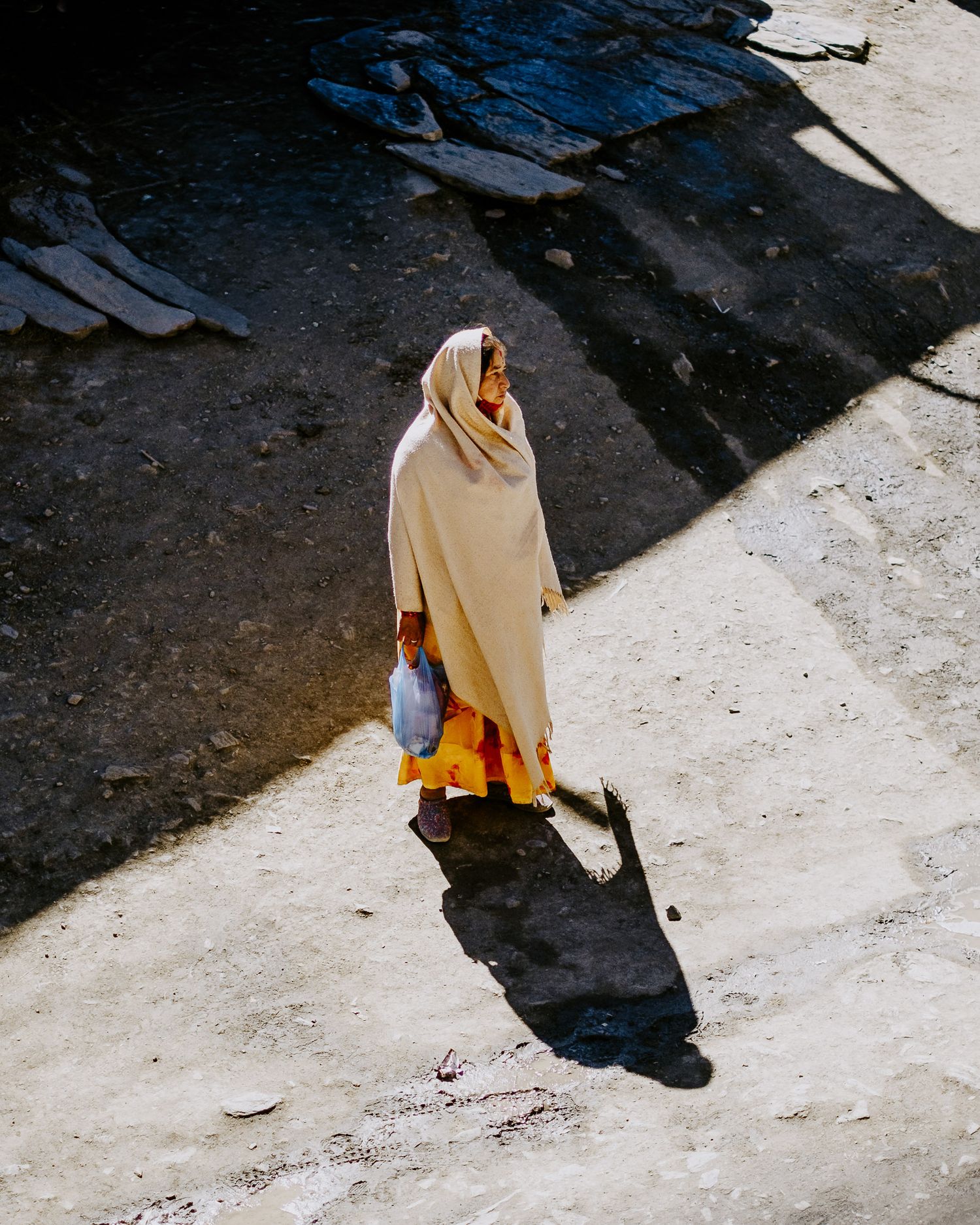 A sequence of images shows a person in a beige coat walking along a concrete surface casting dramatic shadows.