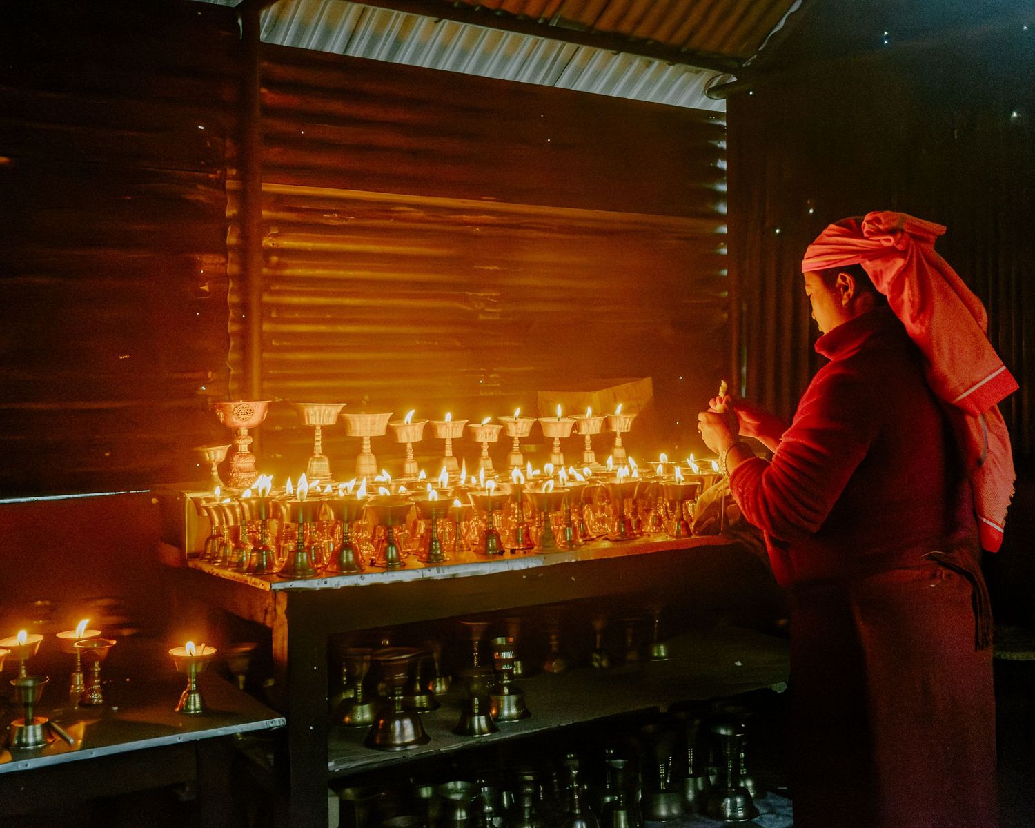 A row of lit candles glowing warmly on a dark wooden bar counter creates an intimate ambiance.