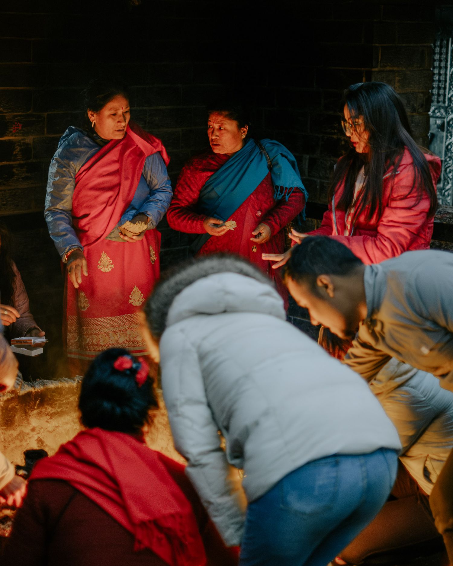 Group gathering in traditional dress around a warm indoor space.