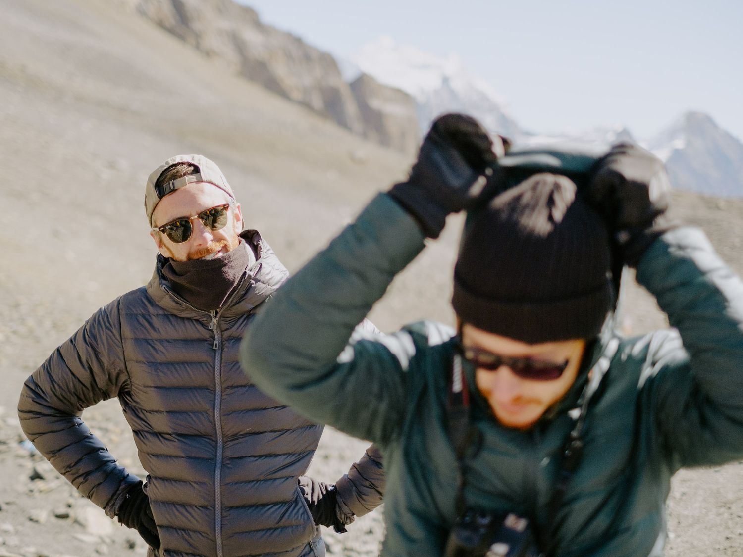 Group of hikers rest at high altitude with mountain peaks visible in the distance.