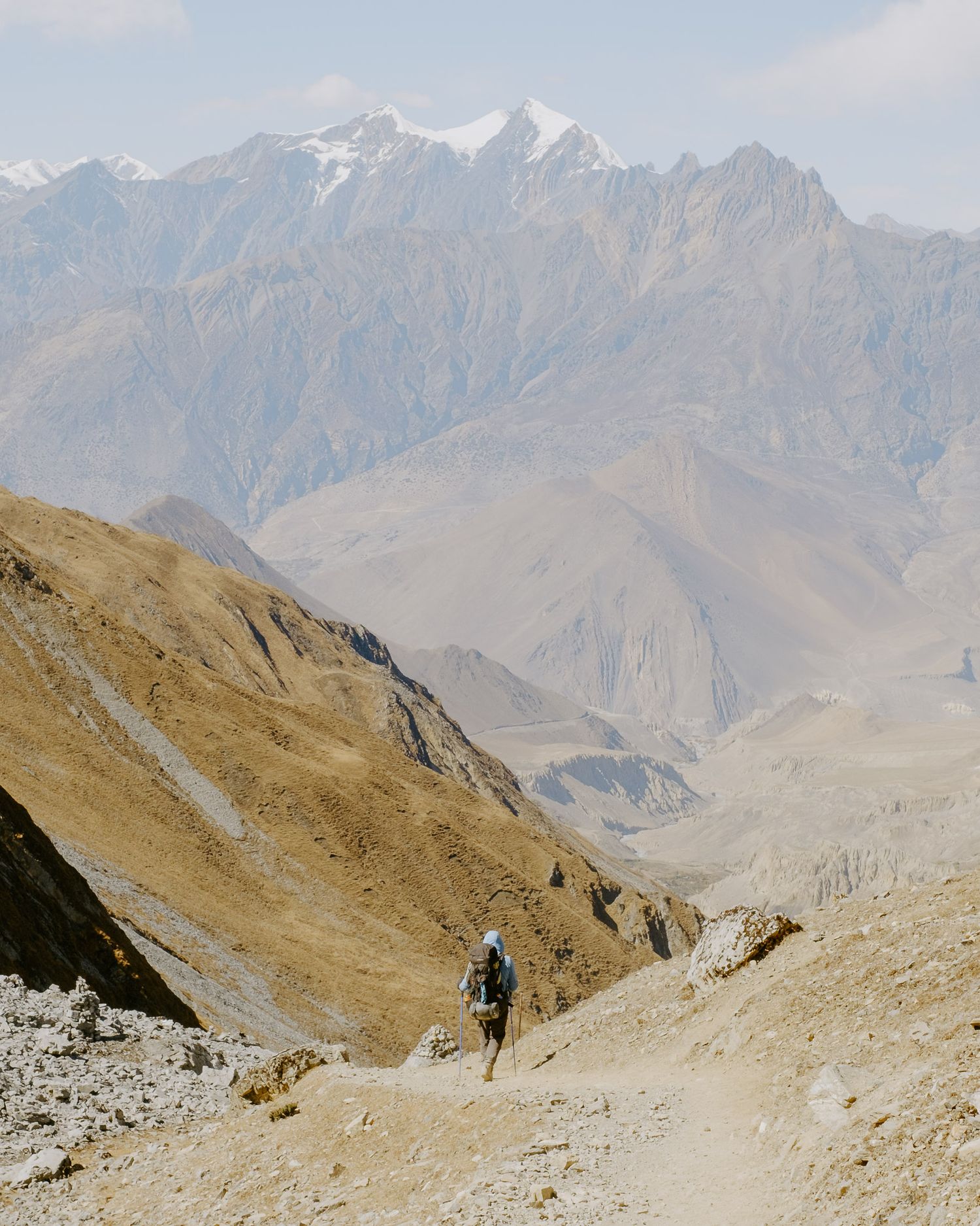 Hiker traversing a steep mountain trail with dramatic valley views below.
