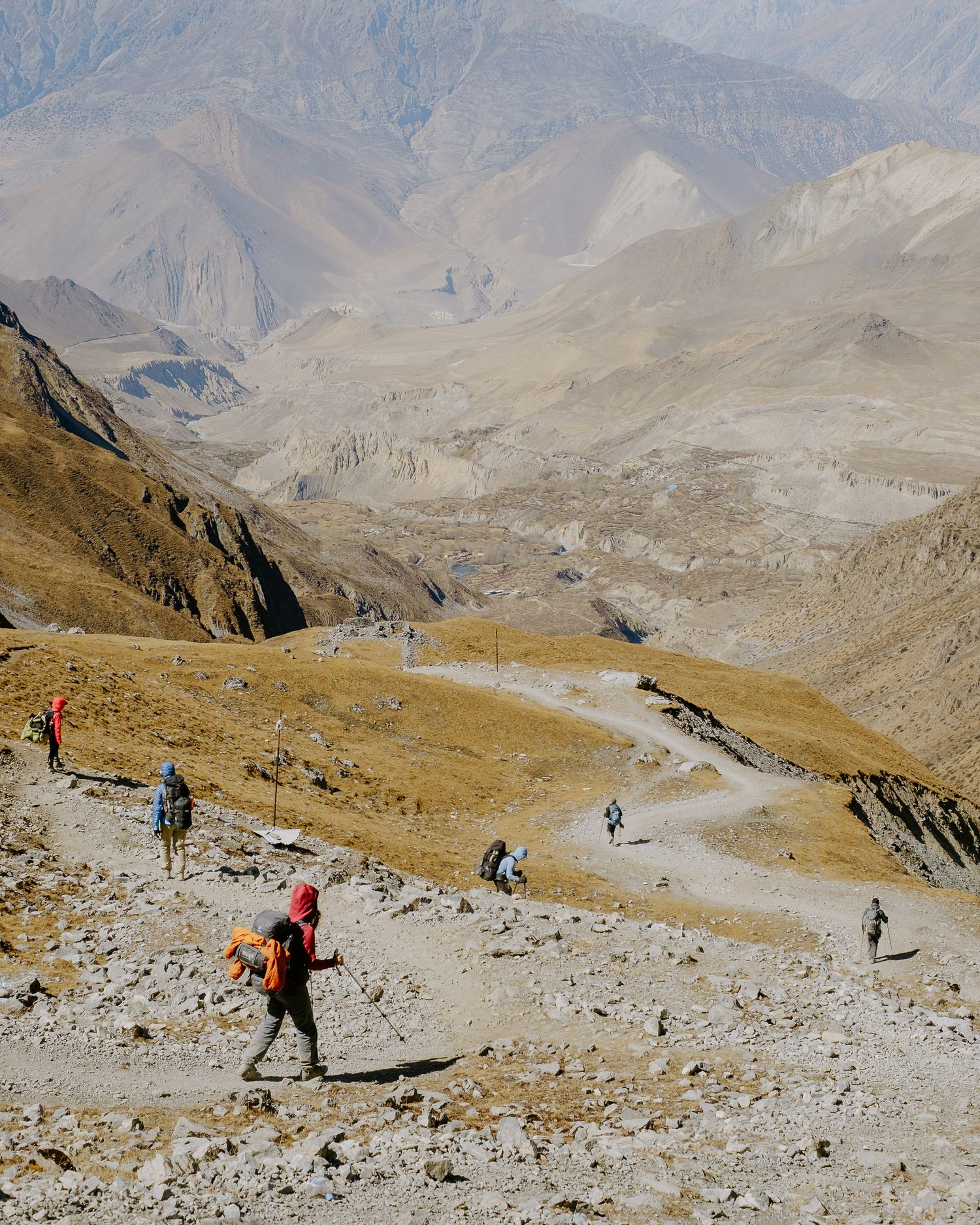 Group of trekkers climbing steep rocky terrain with distant mountain views.