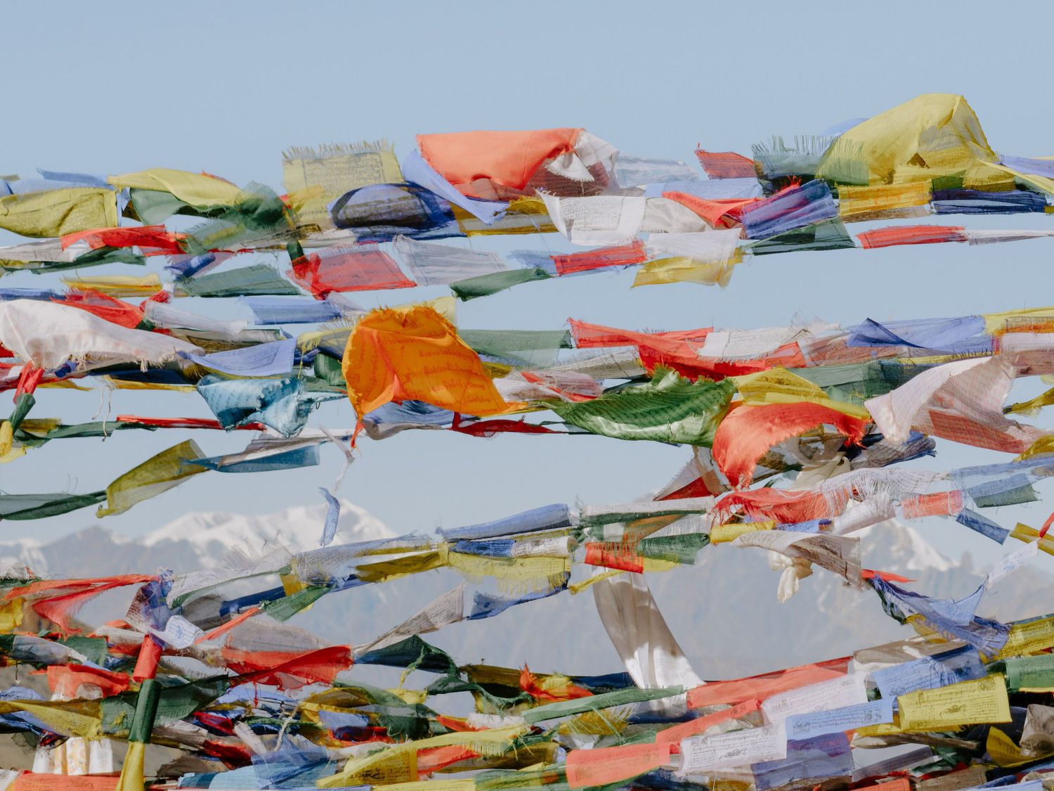 Colorful prayer flags flutter against a bright sky in the Himalayas.
