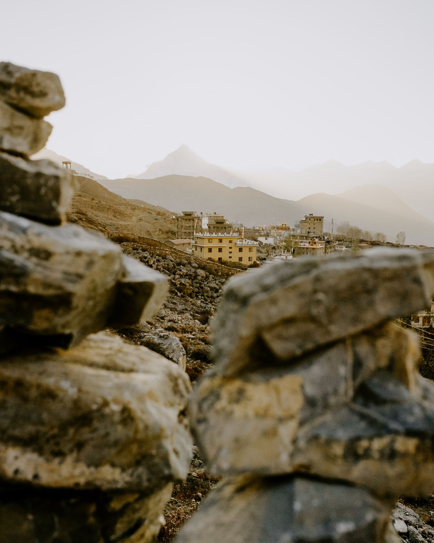 A sepia-toned panoramic view of a mountainous desert landscape with rocky outcrops and distant buildings.