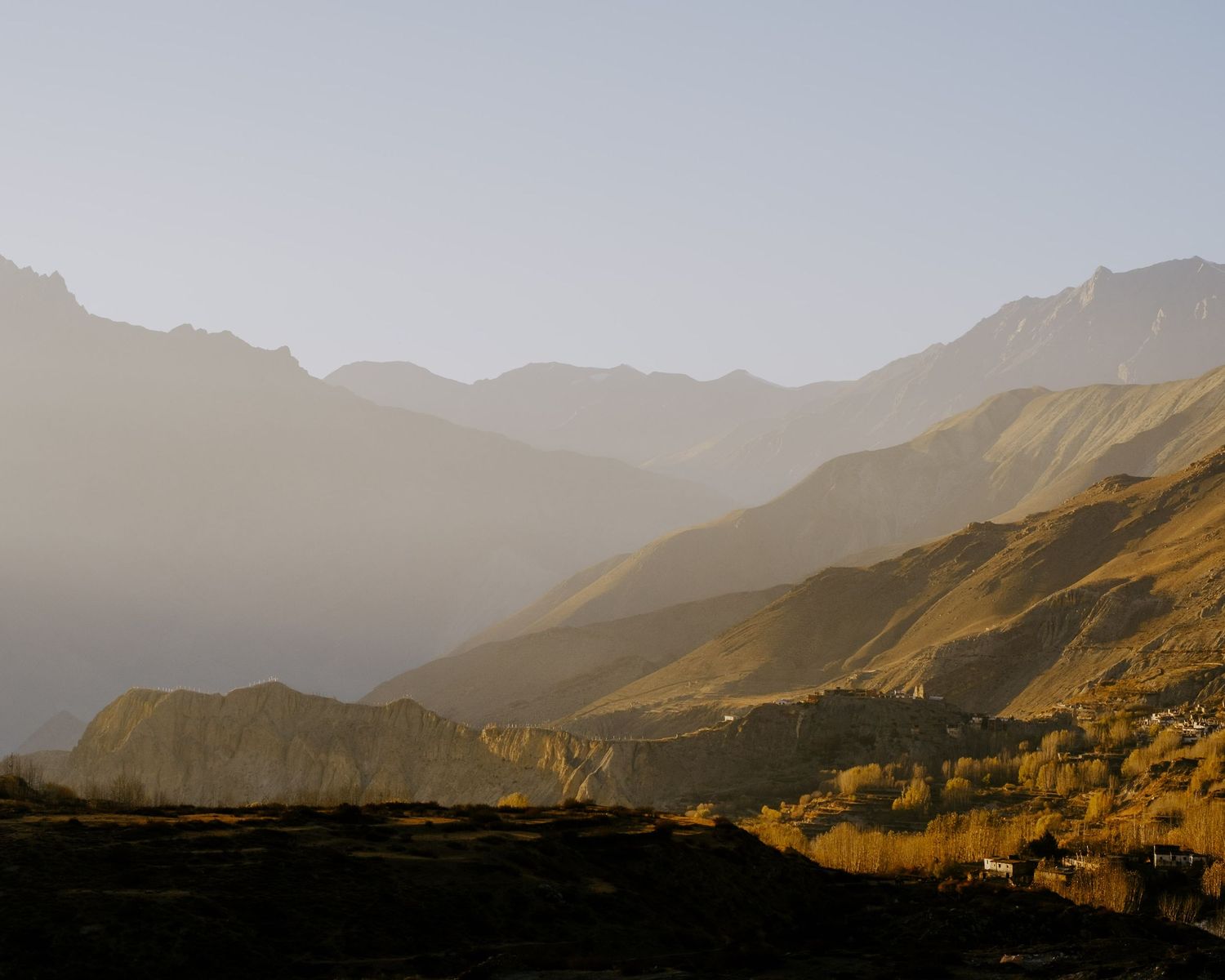 Misty mountain landscape with layered ridges in golden afternoon light.
