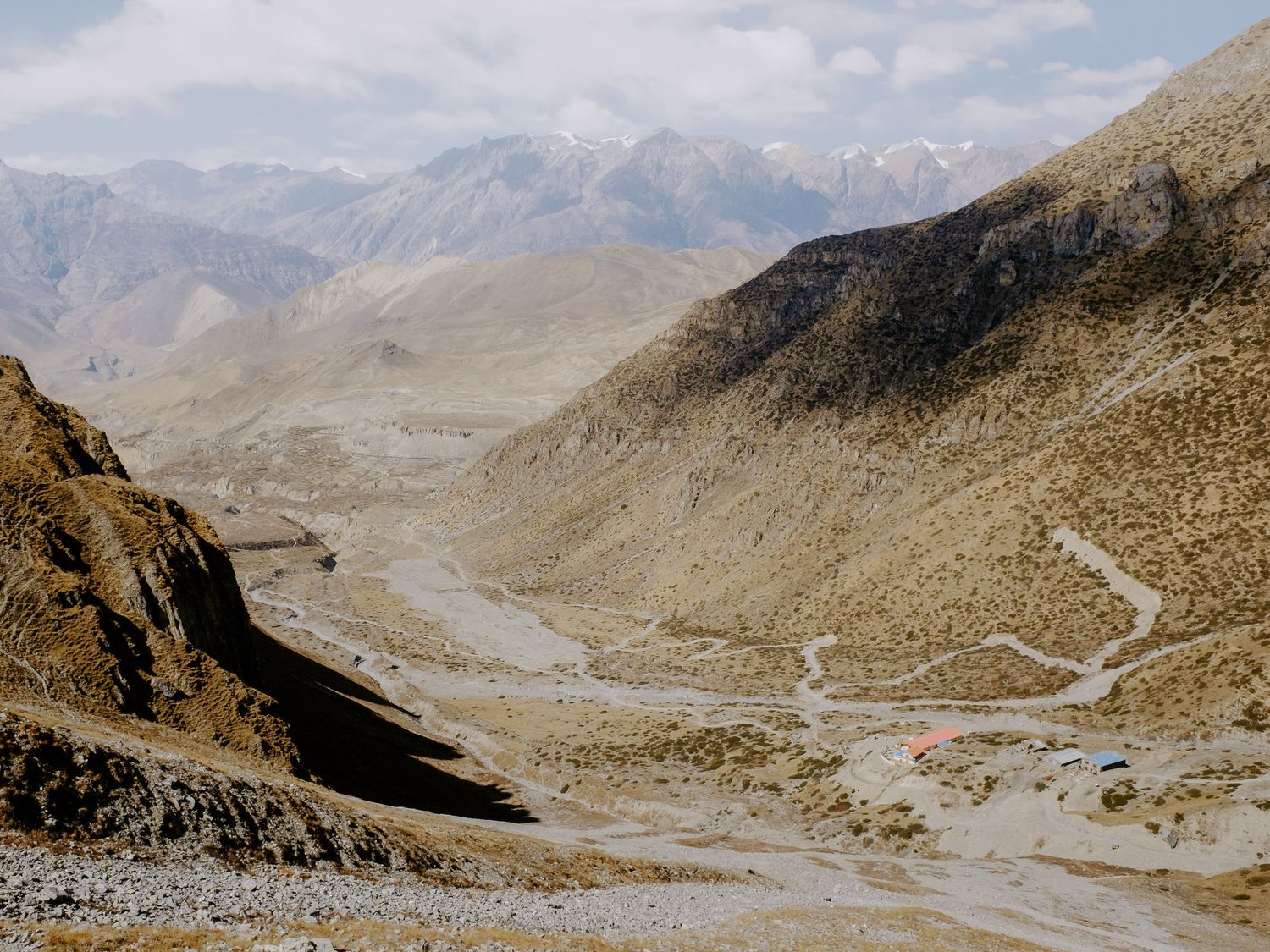 Serpentine mountain road winding through a vast valley surrounded by rugged peaks.