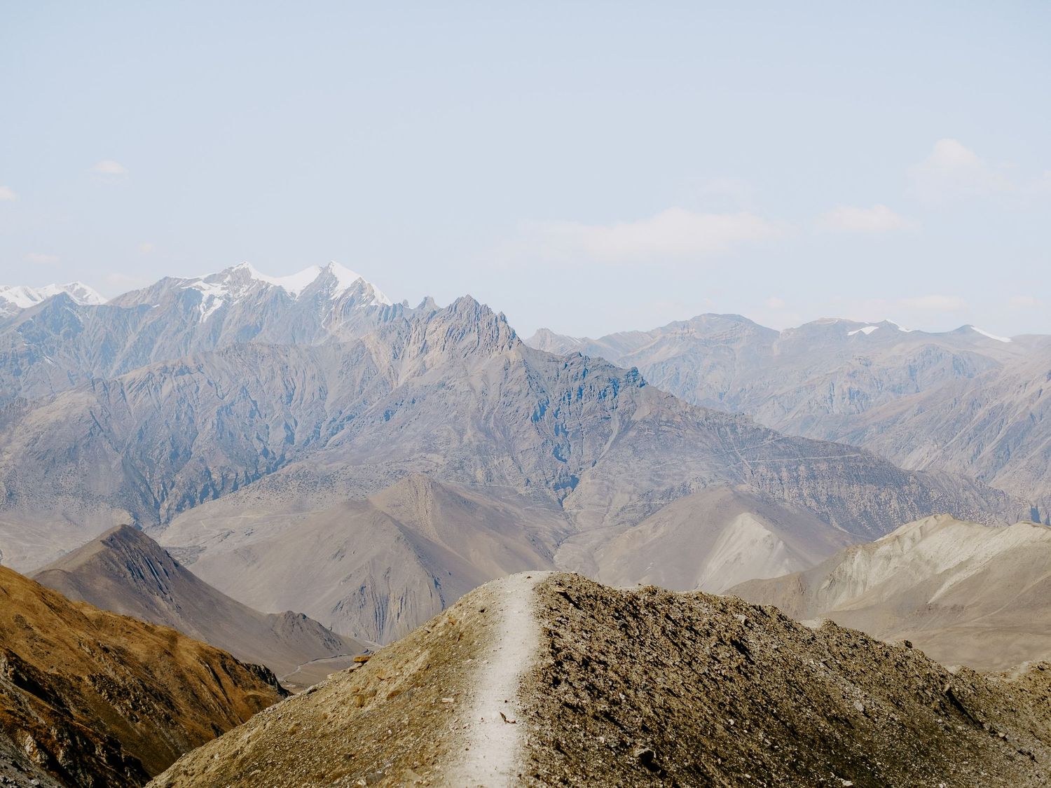 Dramatic mountain ridgeline with jagged peaks stretching into the distance under clear blue skies.