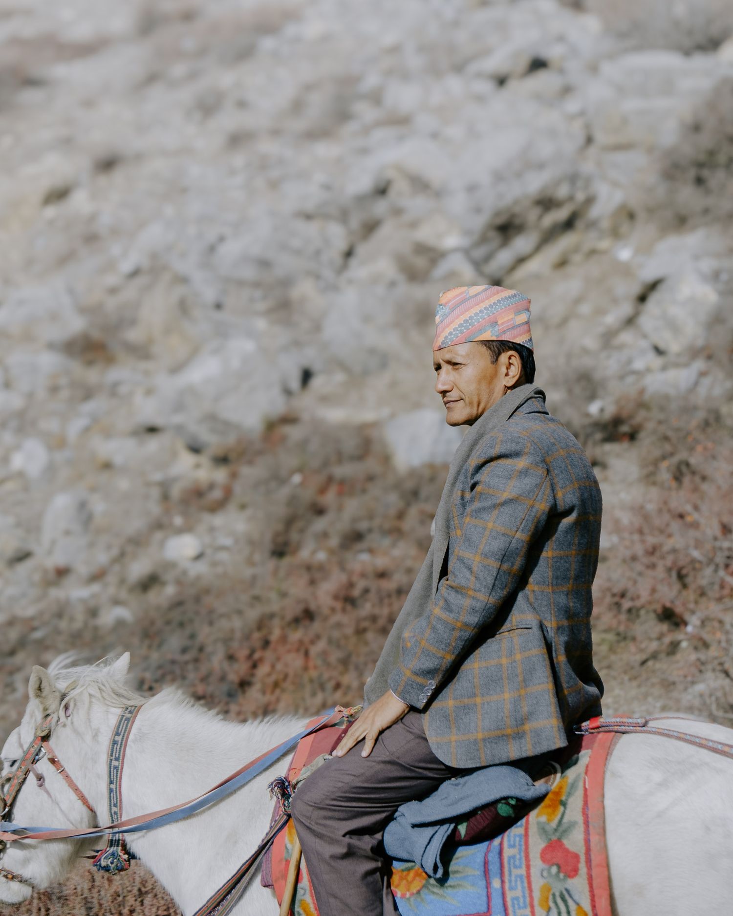 Horseback rider navigating along a mountain path with traditional saddle and gear.