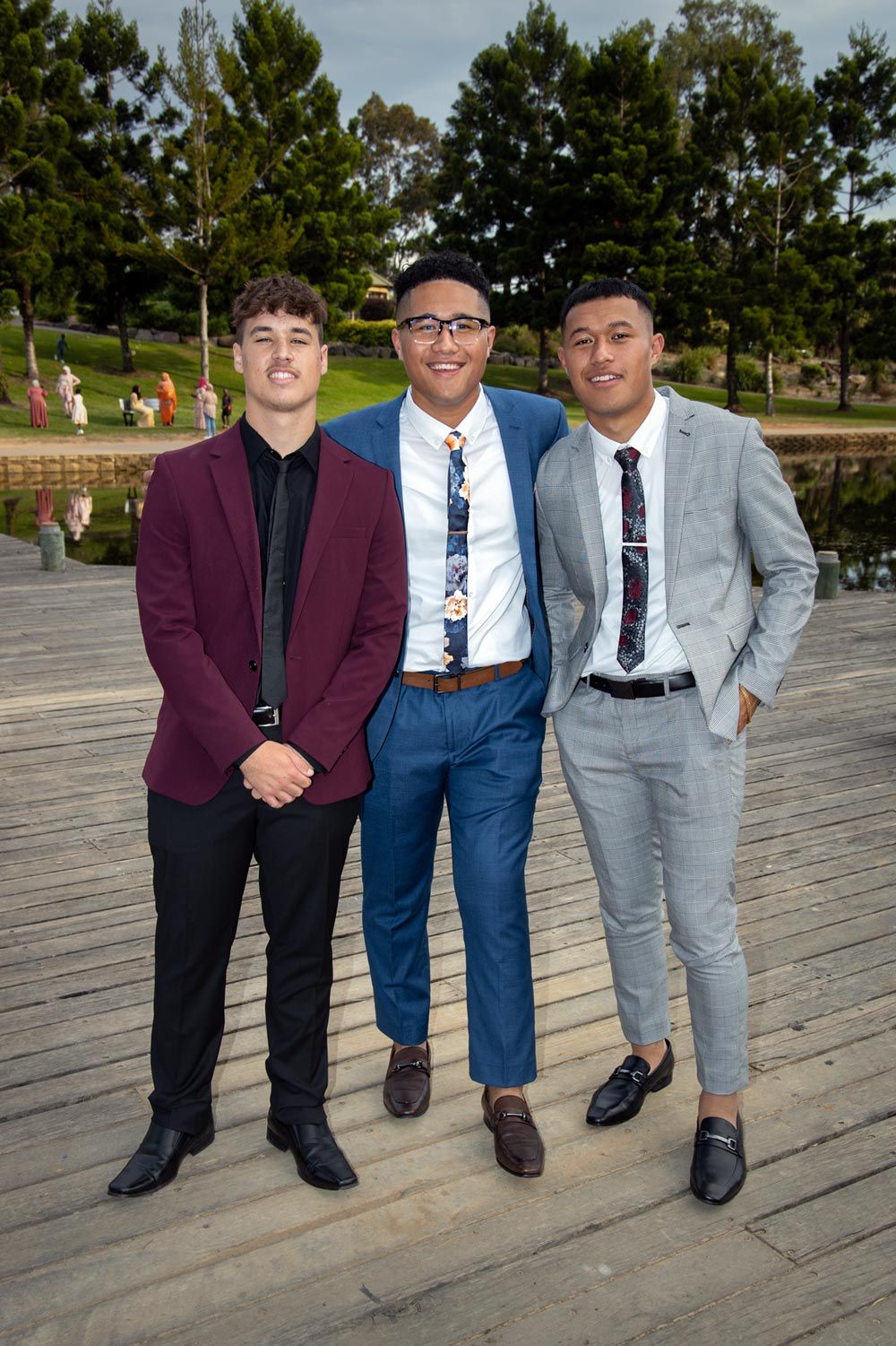 Sydney Event Photography - Three young men in formal attire pose on a wooden deck with pine trees in background.