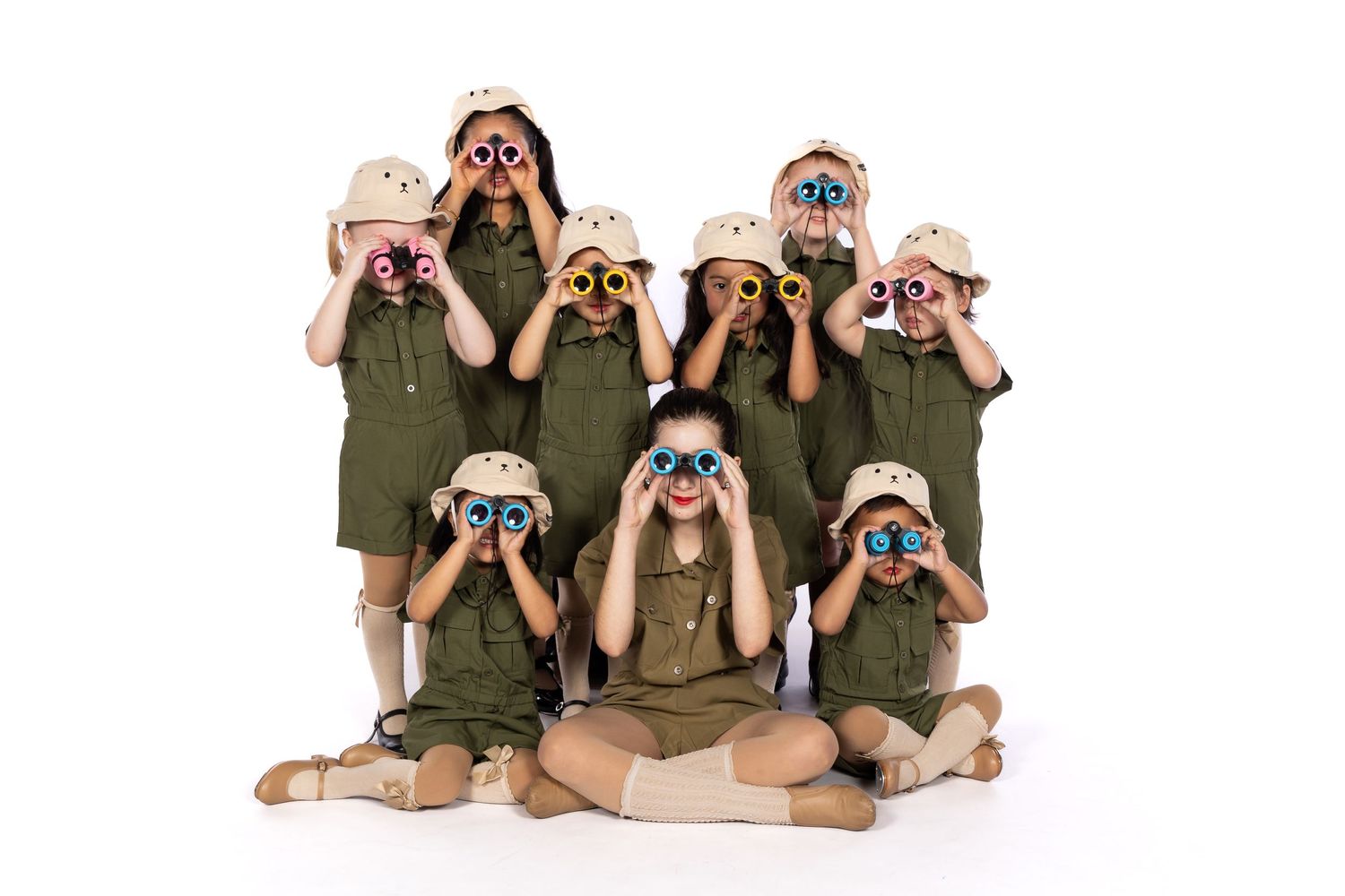 Group wearing safari outfits and hats looking through binoculars in staged photo.