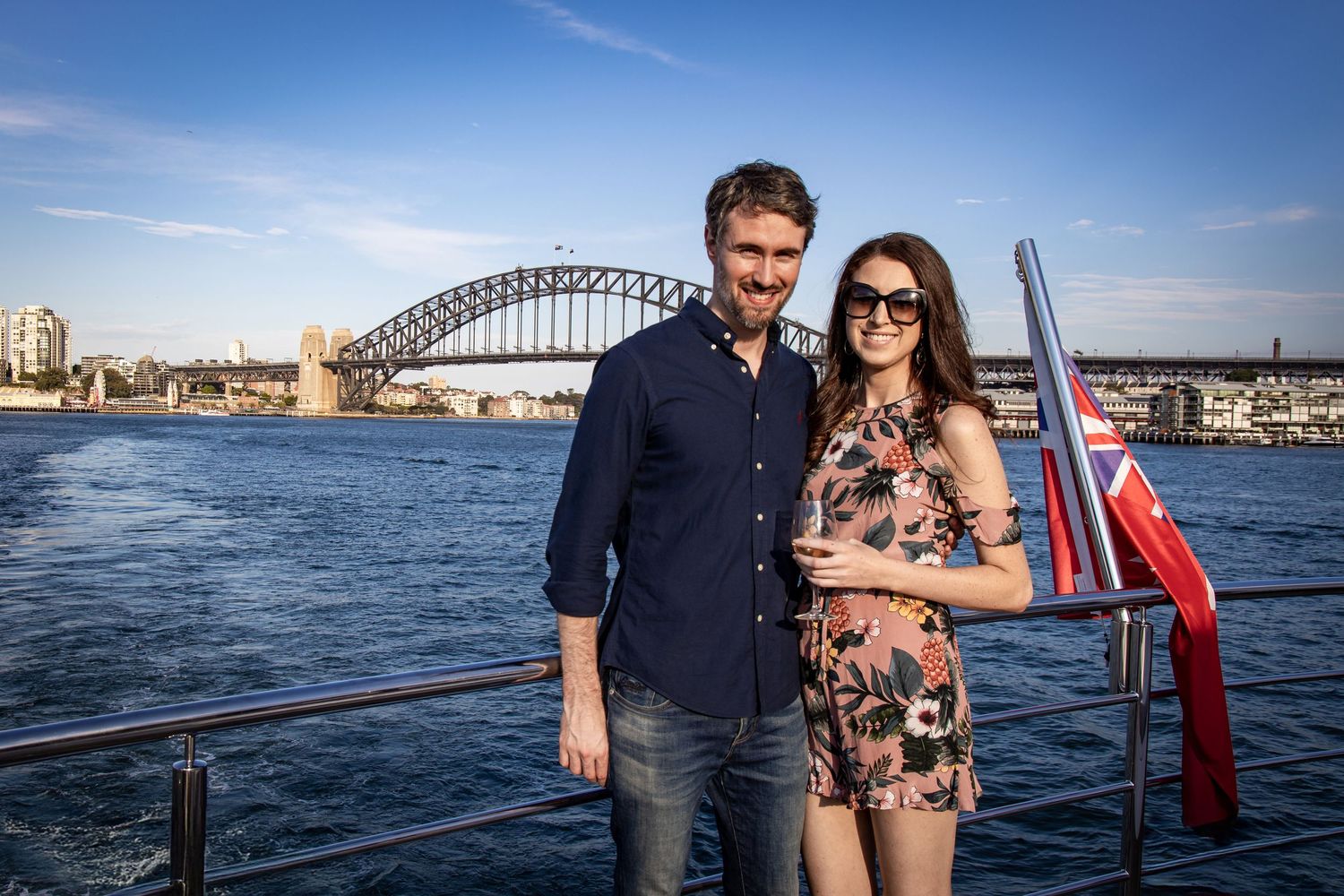 Sydney Event Photography - A couple poses on a boat deck with Sydney Harbour Bridge visible in the background.